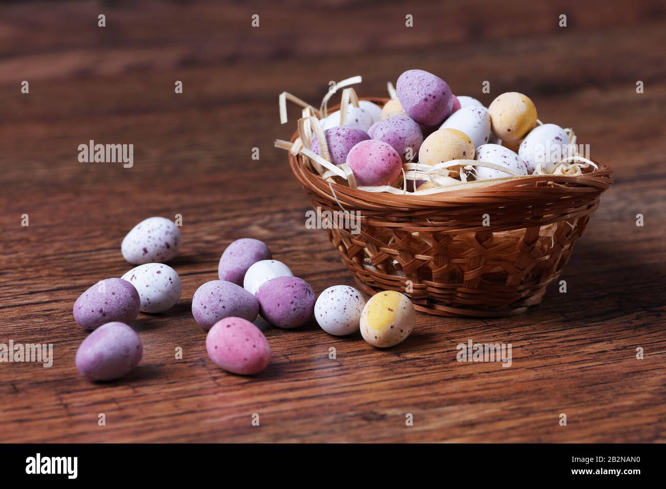 Eine enge Imamge von Ostereiern in einem Korb mit Strohhalm auf Holztisch mit selektivem Fokus und geringer Schärfentiefe Stockfoto