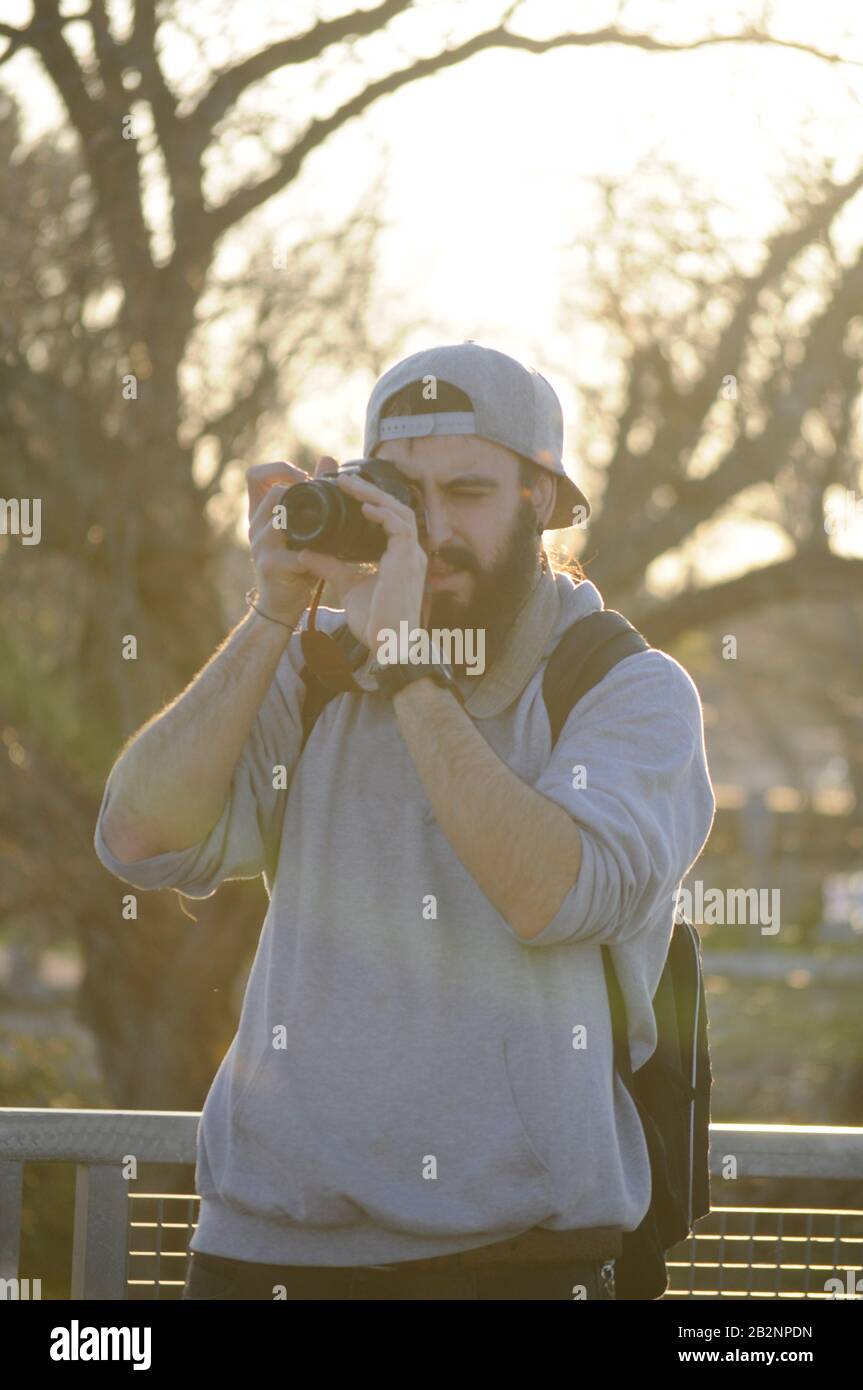 Europäischer Mann fotografiert/ Mann mit grauem Hut fotografiert/ Fotograf macht seine Arbeit/ Junger Mann mit Bart mit dslr-Kamera Stockfoto