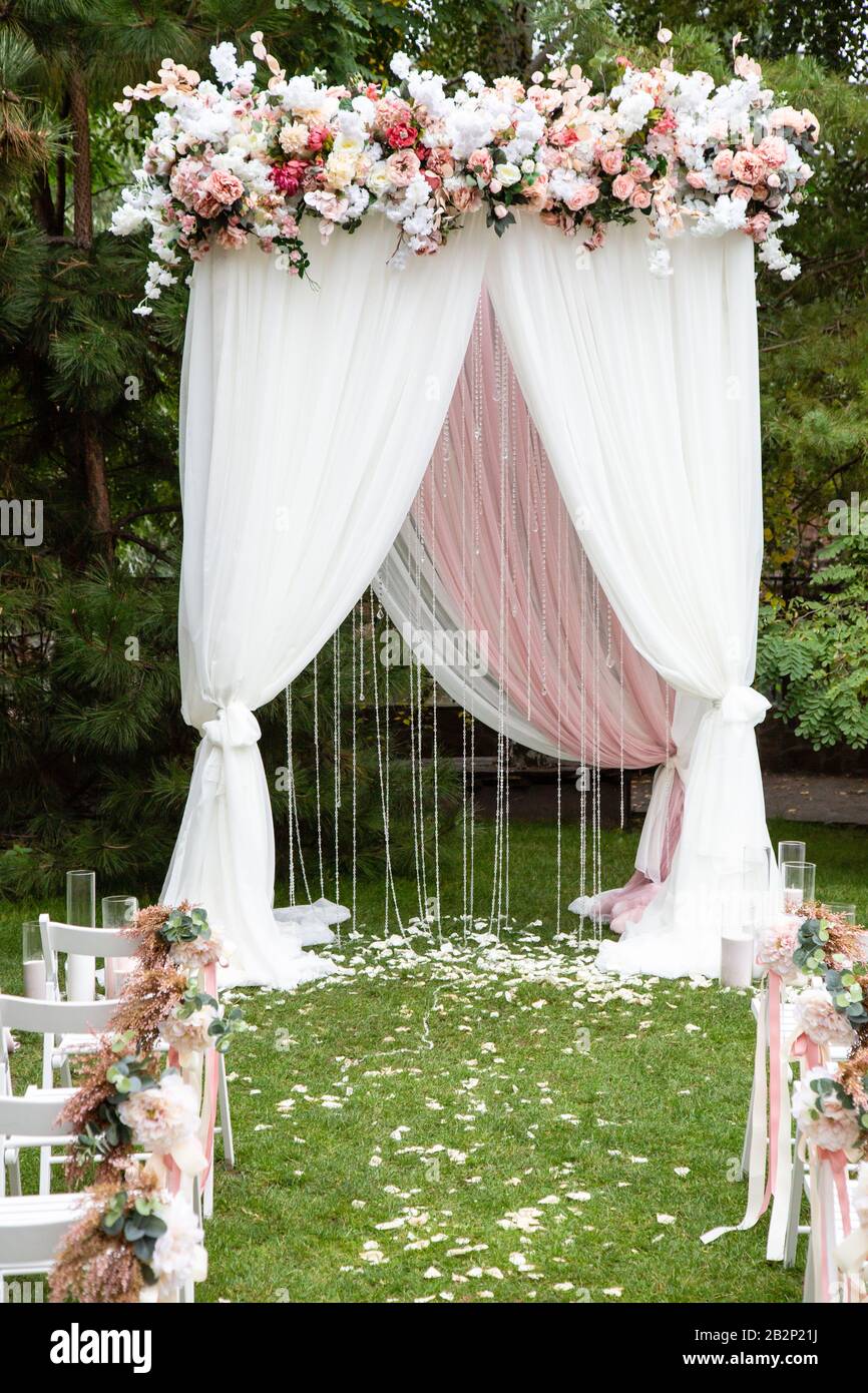 Hochzeit Bogen mit Blumen im Freien eingerichtet. Schöne Hochzeit eingerichtet. Trauung im Garten Stockfoto