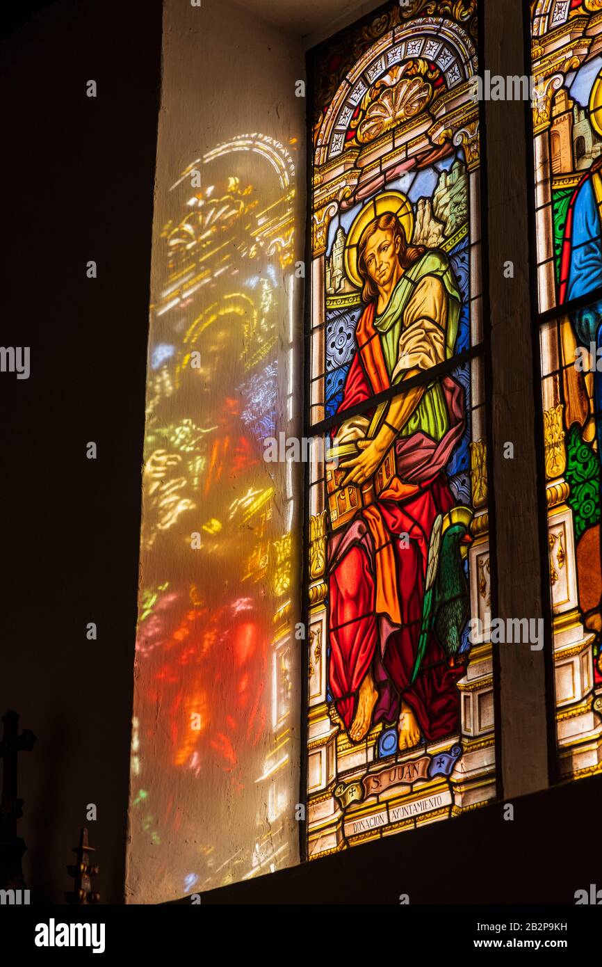 Das Sonnenlicht strömt durch Glasfenster mit Bildern von St. Johannes, San Juan und San Marco in der Kirche Nuestra Senora de Stockfoto