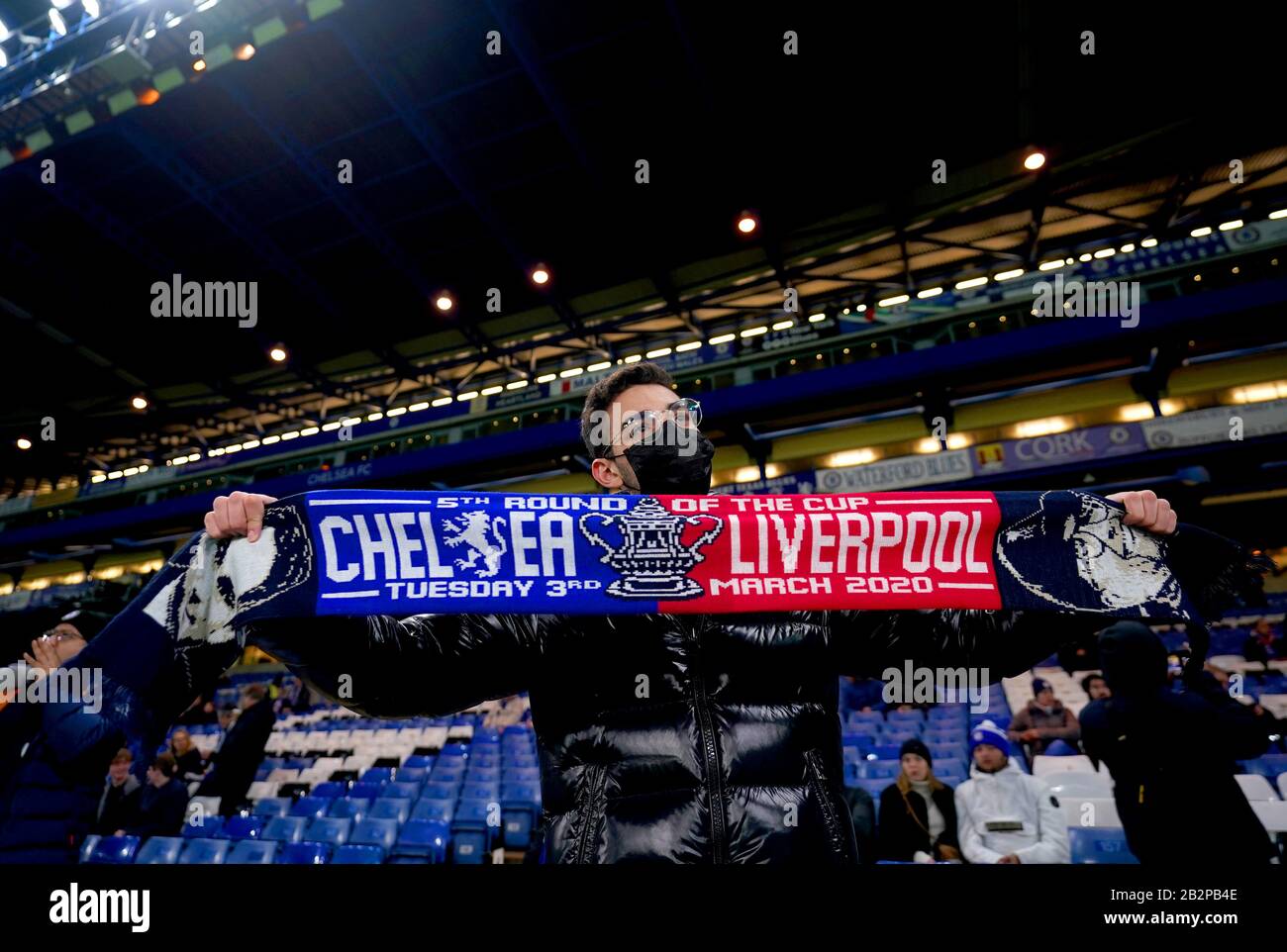 Ein Fan, der eine Gesichtsmaske trägt, hält vor Beginn des fünften Spiels im FA Cup an der Stamford Bridge, London, ein Half Match Schal. Stockfoto