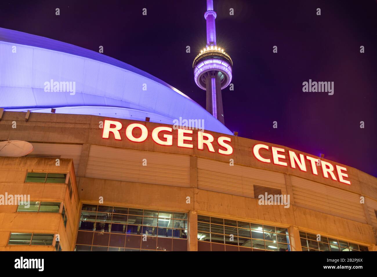 Rogers Centre Schild an der Spitze des berühmten Sportstadions, mit dem CN Tower im Hintergrund oben. Stockfoto