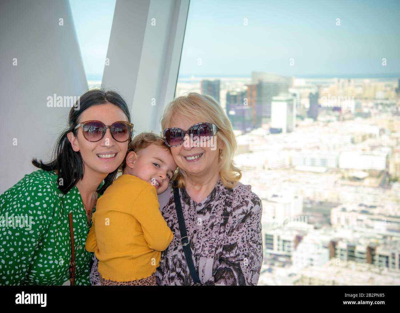 Porträt von drei Generationen mit hintergrundbeleuchteter Stadtlandschaft im Hintergrund aus Dubai Frame UAE Stockfoto