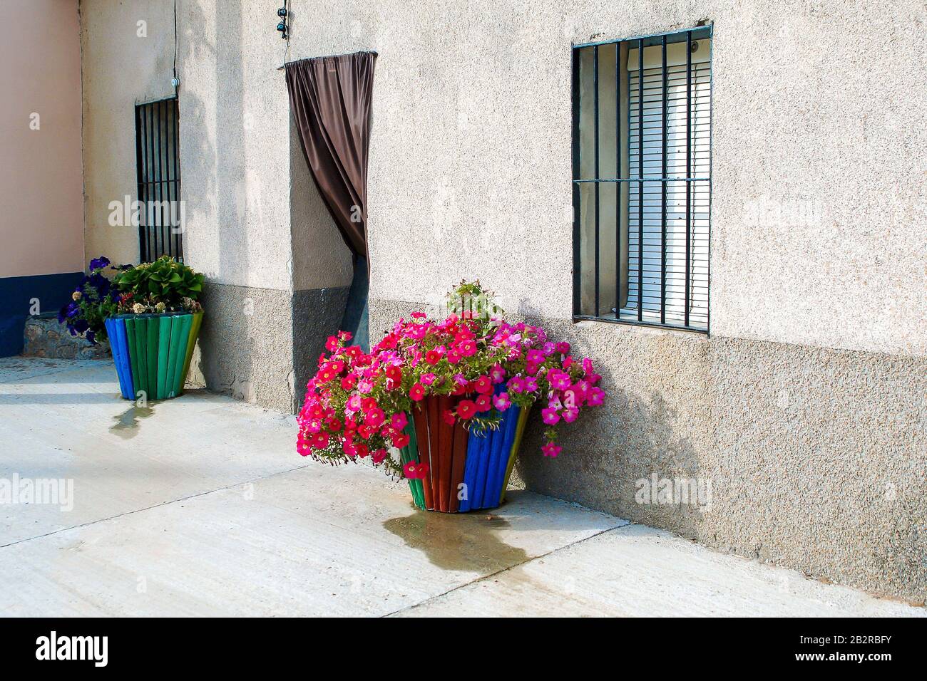 Fassade des Hauses im Dorf mit Fenstern mit Bars und zwei Töpfen. Stockfoto