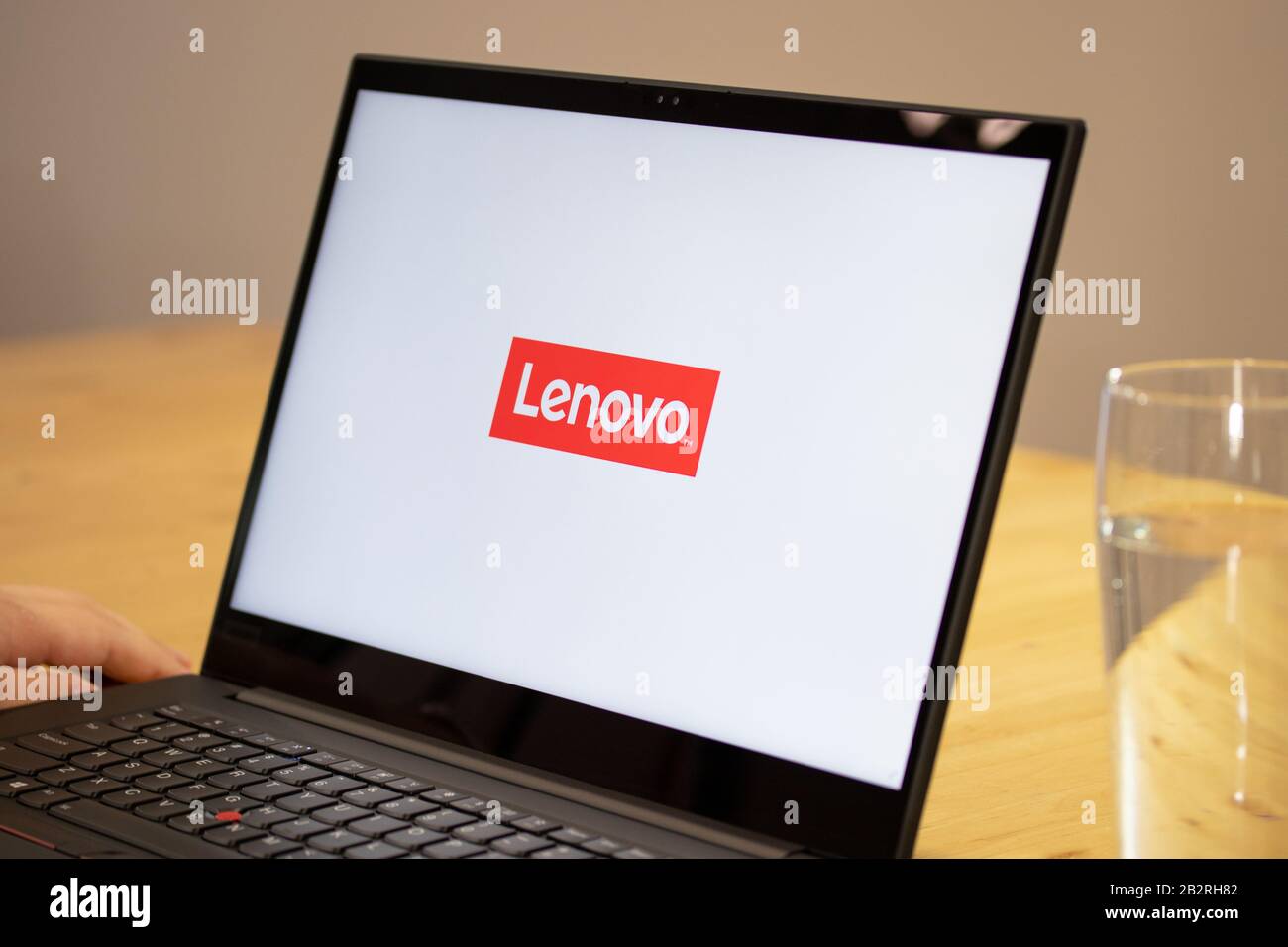 Person, die einen Schreibtisch mit einem Lenovo Laptop mit dem Lenovo Logo auf dem Bildschirm verwendet. Stockfoto
