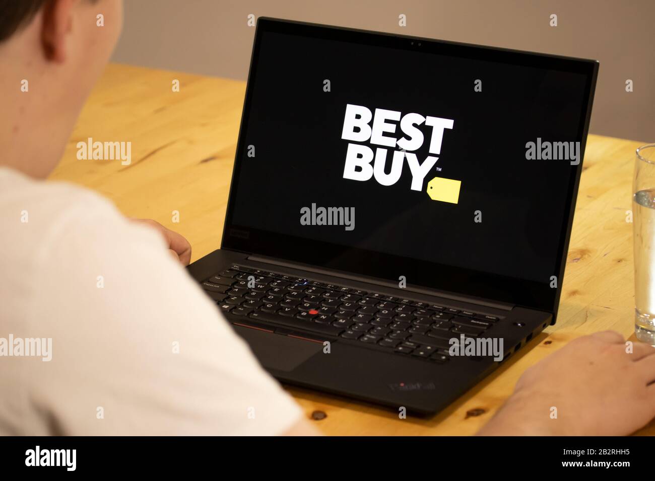 Mann, der an einem Schreibtisch sitzt und einen Laptop mit dem Best Buy-Logo auf dem Bildschirm verwendet. Stockfoto