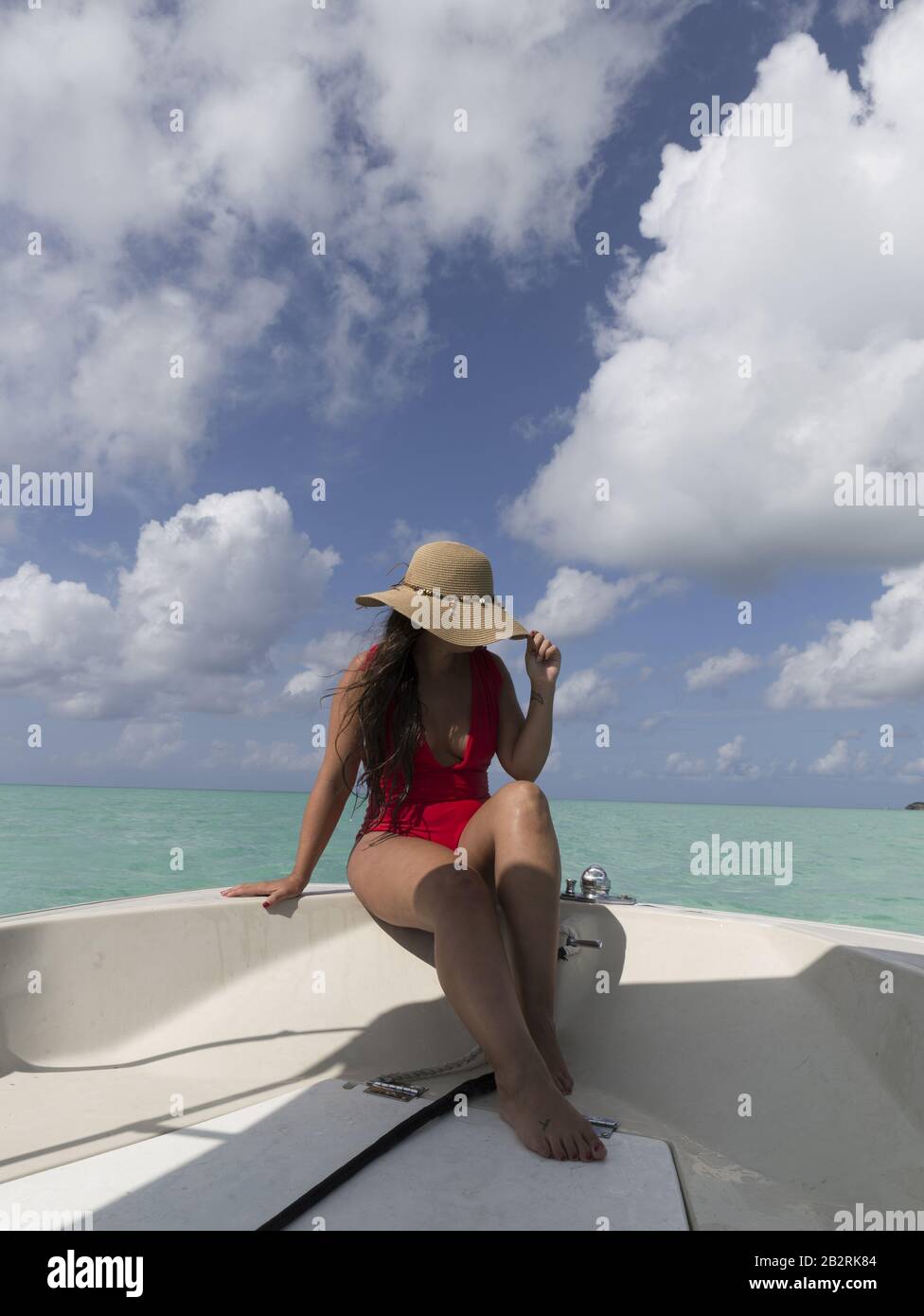 Schöne Frau in einem rosa Bikini mit einem Floppy breit hut im Boot unter dem blauen Himmel Stockfoto