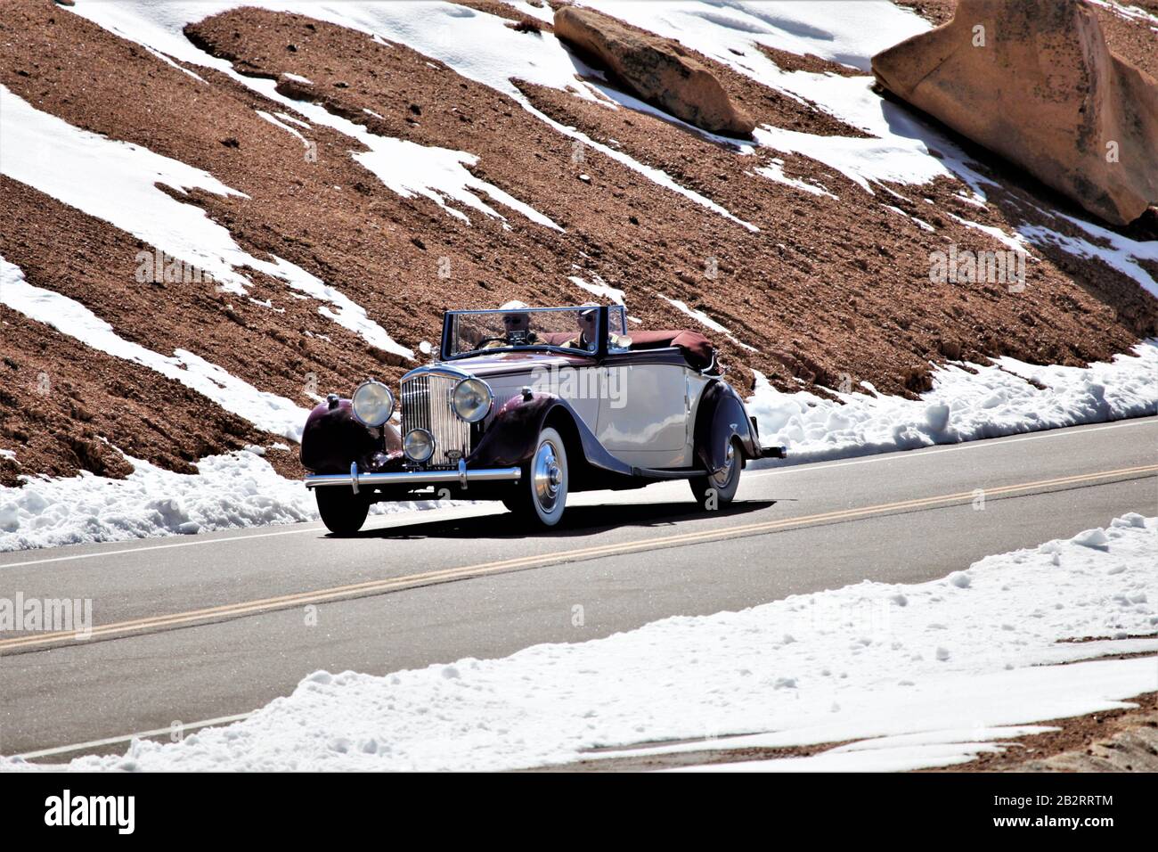 Die langsame und gefährliche Straße auf Pikes Peak in Colorado in den USA mit einem älteren Cabrio an einem sonnigen Tag einige mit Kopierraum und klarem Himmel Stockfoto