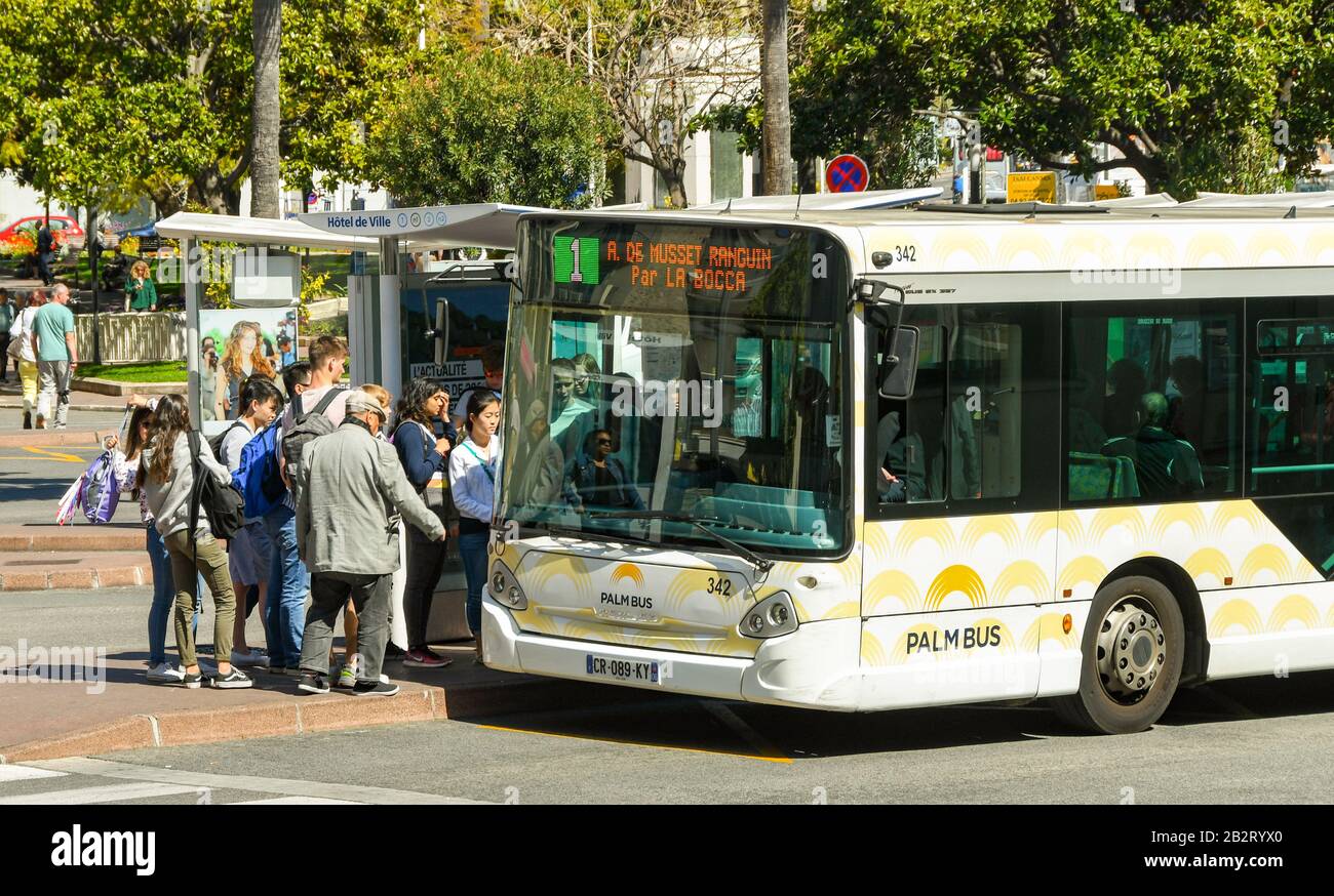 Cannes, FRANKREICH - APRIL 2019: Menschenmenge, die an einer Bushaltestelle im Zentrum von Cannes in einen Bus einsteigen. Stockfoto Cannes, FRANKREICH - APRIL 2019: Menschenmenge, die an einer Bushaltestelle im Zentrum von Cannes in einen Bus einsteigen. Stockfoto