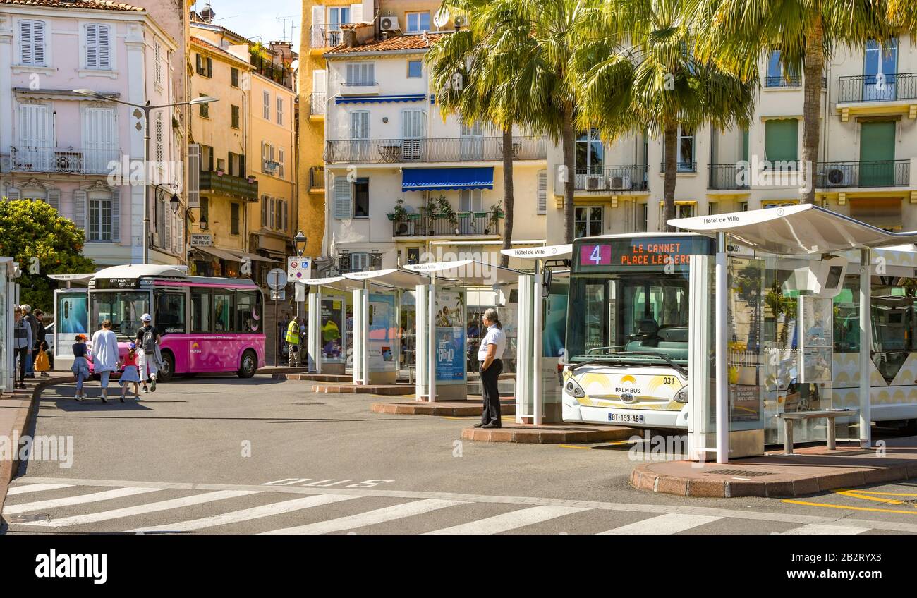 Cannes, FRANKREICH - APRIL 2019: Busse im Busbahnhof im Zentrum von Cannes. Ein kleiner Elektrobus ist im Hintergrund abgestellt. Stockfoto