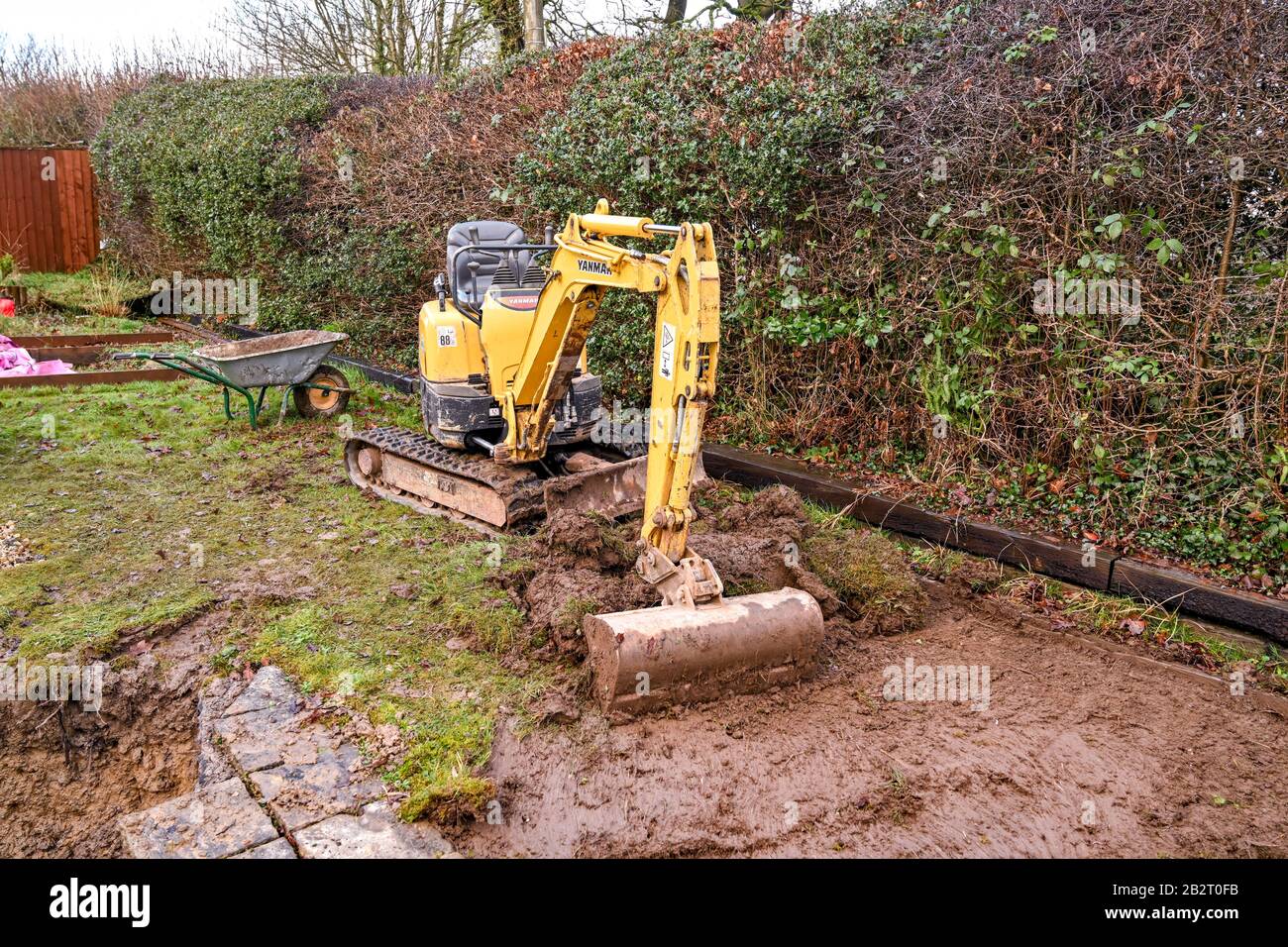 Cardiff, WALES - JANUAR 2020: Minibagger graben den Rasen im Hintergarten eines Wohngrundstücks auf Stockfoto
