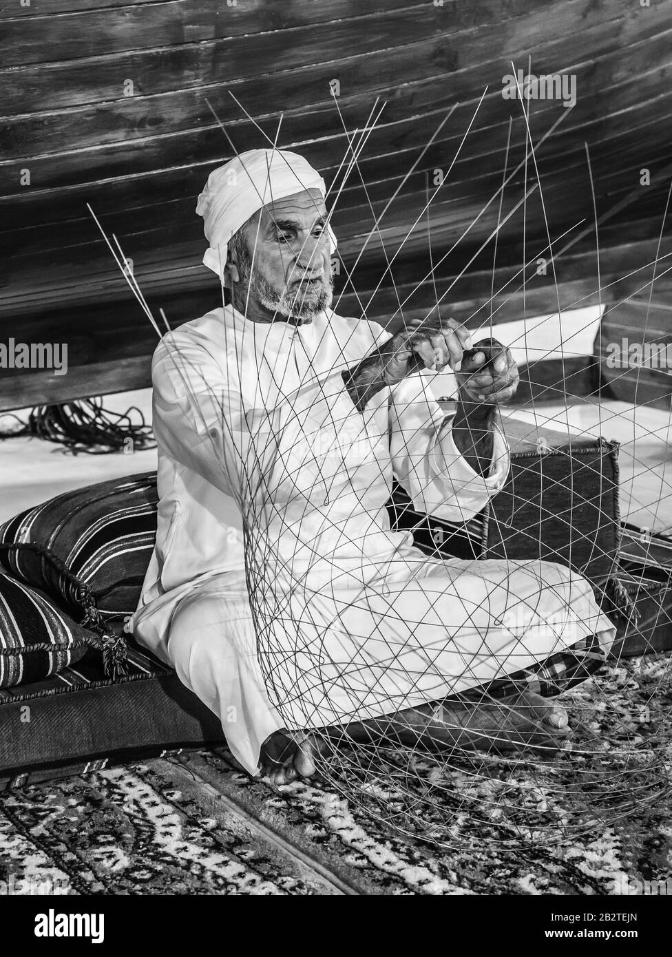 Dubai, VAE - 4. DEZEMBER 2017: Der alte Mann webt ein Fischernetz, um Gäste im Pavillon der Vereinigten Arabischen Emirate, Global Village, zu treffen Stockfoto