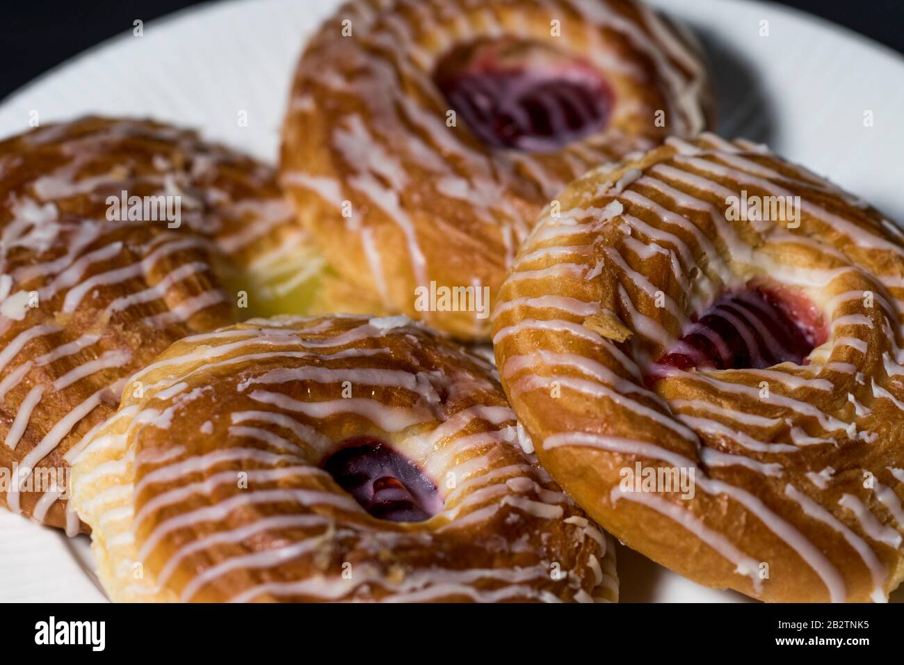 Dänisches Gebäck auf einem Teller. Frisch vereiste süße Brötchen zum Frühstück und Dessert. Hausgemachte dänische Gebäckstücke. Köstliche Backwaren. Stockfoto
