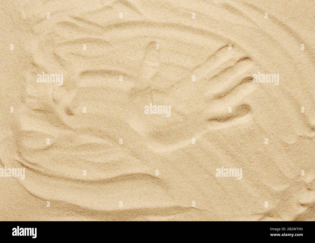Tropischer Sandhintergrund. Sandstrandstruktur mit Handdruck. Draufsicht Stockfoto