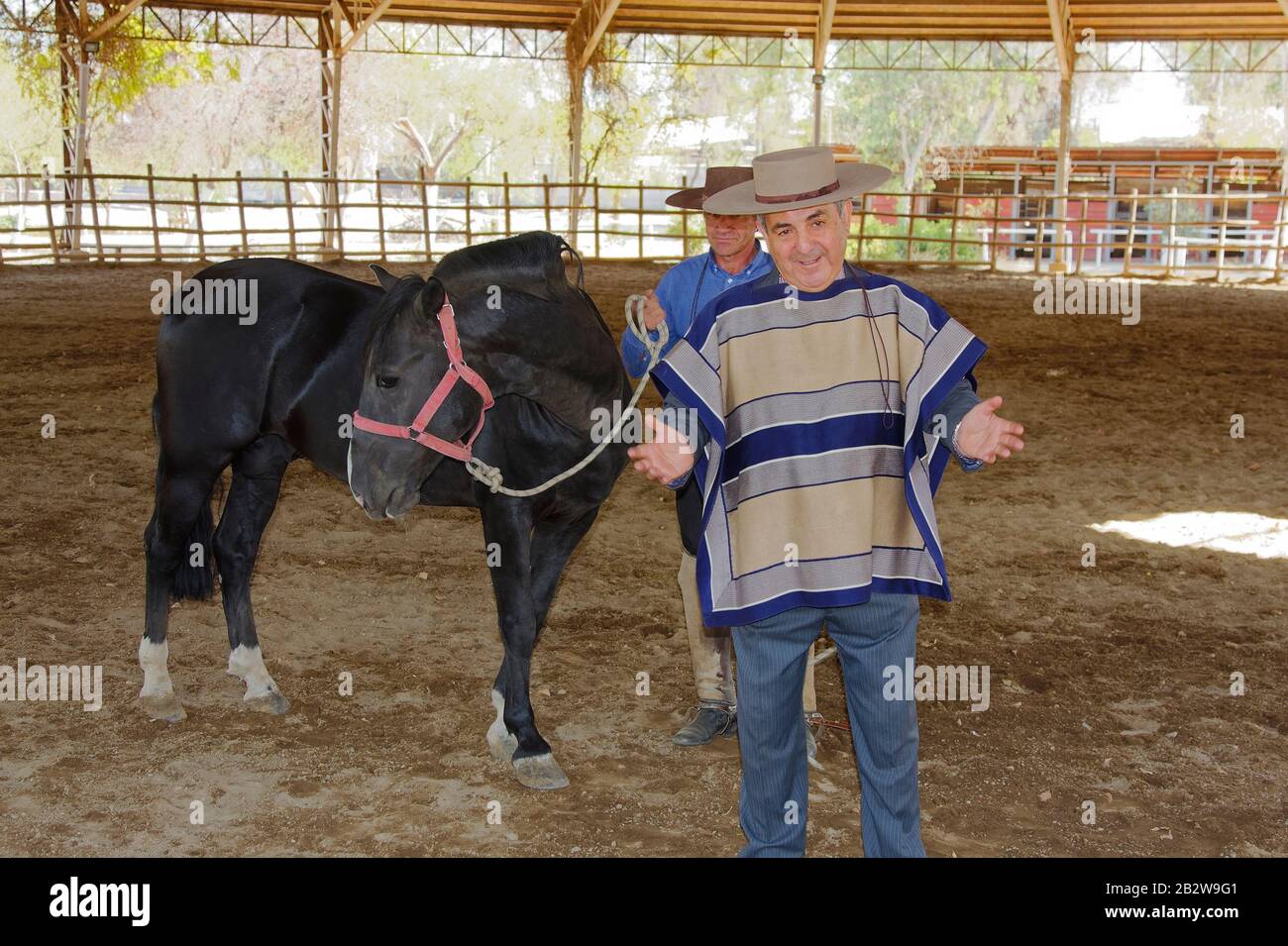 Chilenischer Cowboy erklärt Tradions, Pferd; Huaso; trägt traditionelle Kleidung, Chupalla, Poncho, Dirt-Practice-Ring, Huaso Training Camp; Santiago; C. Stockfoto