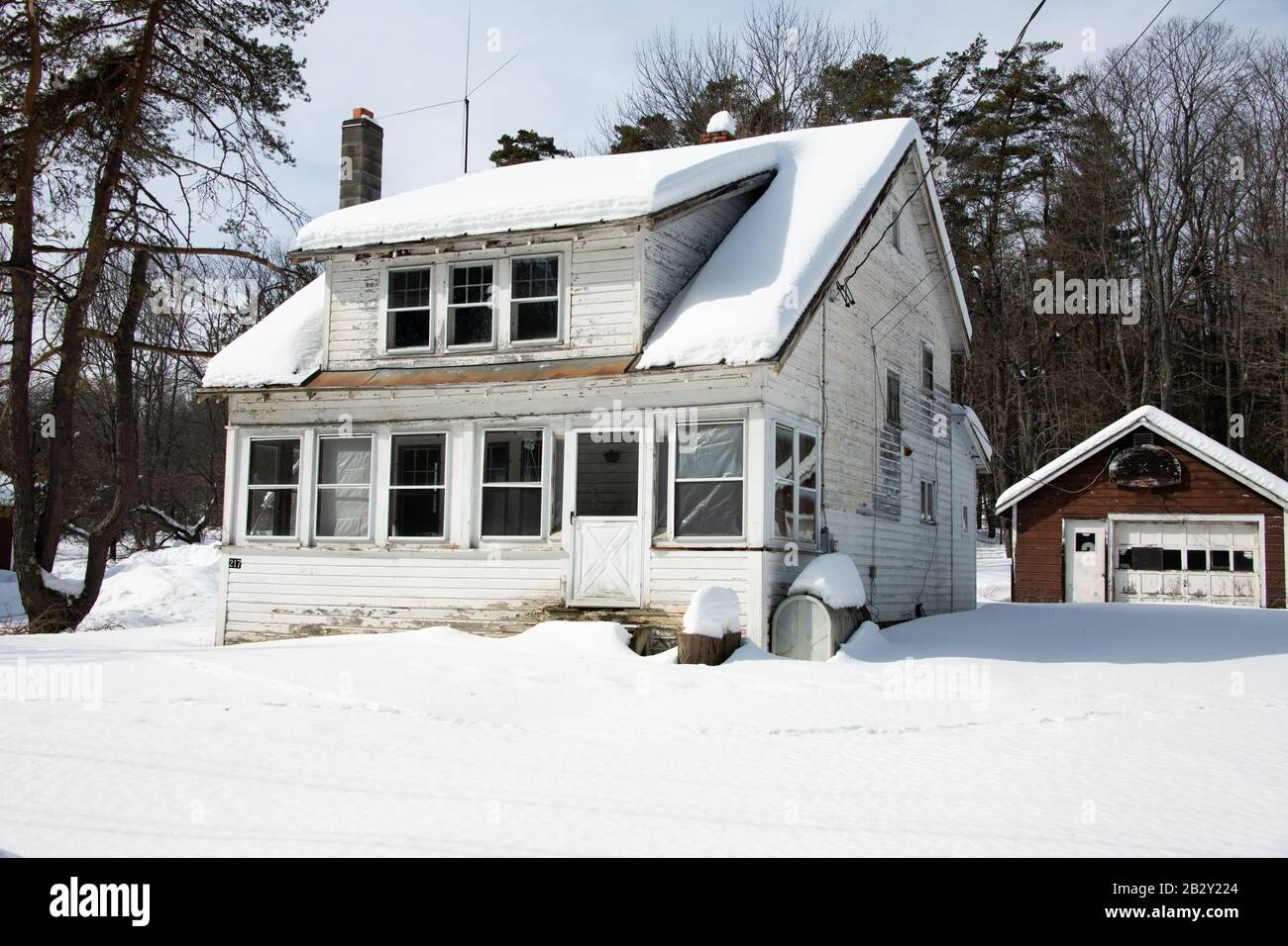 Ein altes, unbesetztes heruntergefallendes Haus, das nach einem Wintersturm im Spekulanten, NY USA, mit Schnee bedeckt war Stockfoto