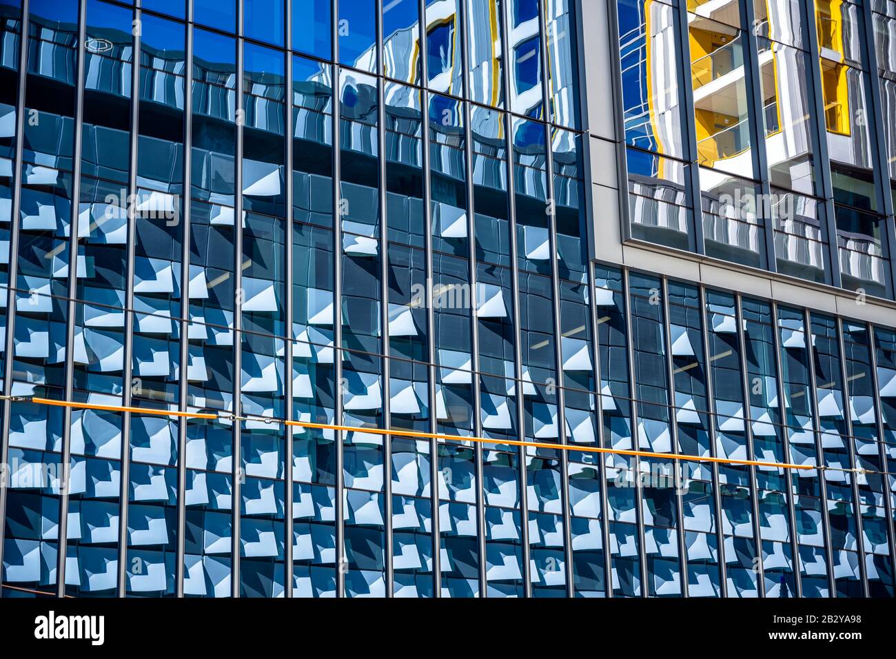 Reflektierende Elemente der modernen Stadtarchitektur dekorative abstrakte, fixierte Außenwände eines sonnenbeleuchteten mehrstöckigen Gebäudes, das in der for hergestellt wurde Stockfoto