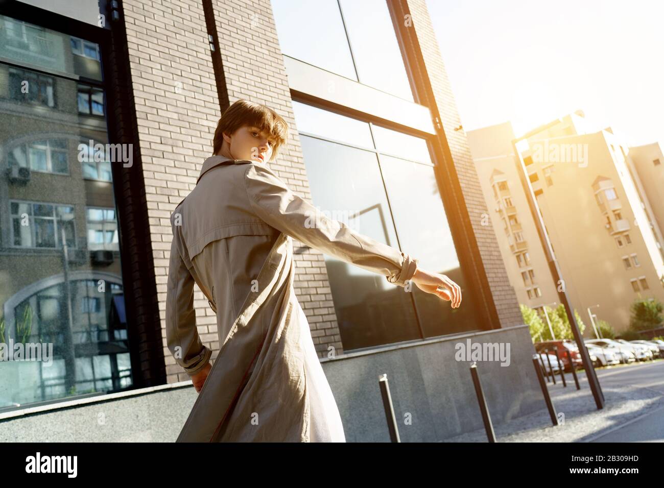 Modemädchen tragen einen stilvollen Trenchcoat, der auf der Straße in der Stadt mit Blick auf die Kamera läuft. Stockfoto