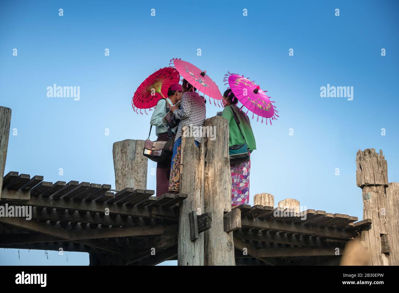 Mandalay, Myanmar - Januar 2020: Lokale birmanische Händler mit bunten Regenschirmen verkaufen Souvenirs an Touristen an der berühmten U-Bein-Brücke. Stockfoto