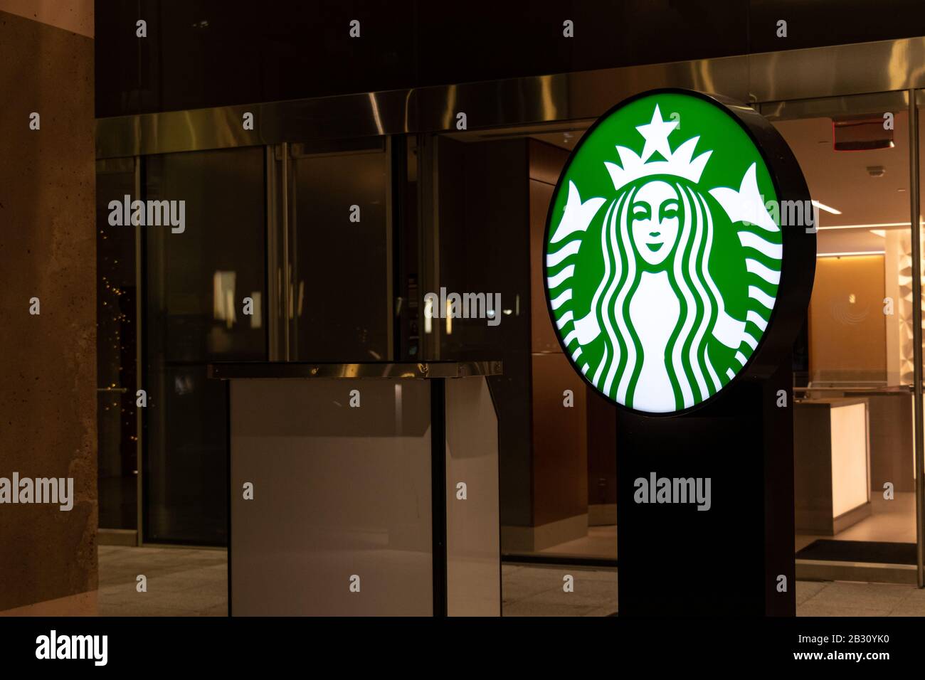 Das Starbucks Coffee Logo leuchtet nachts vor einem Café in einem Hotel auf. Stockfoto