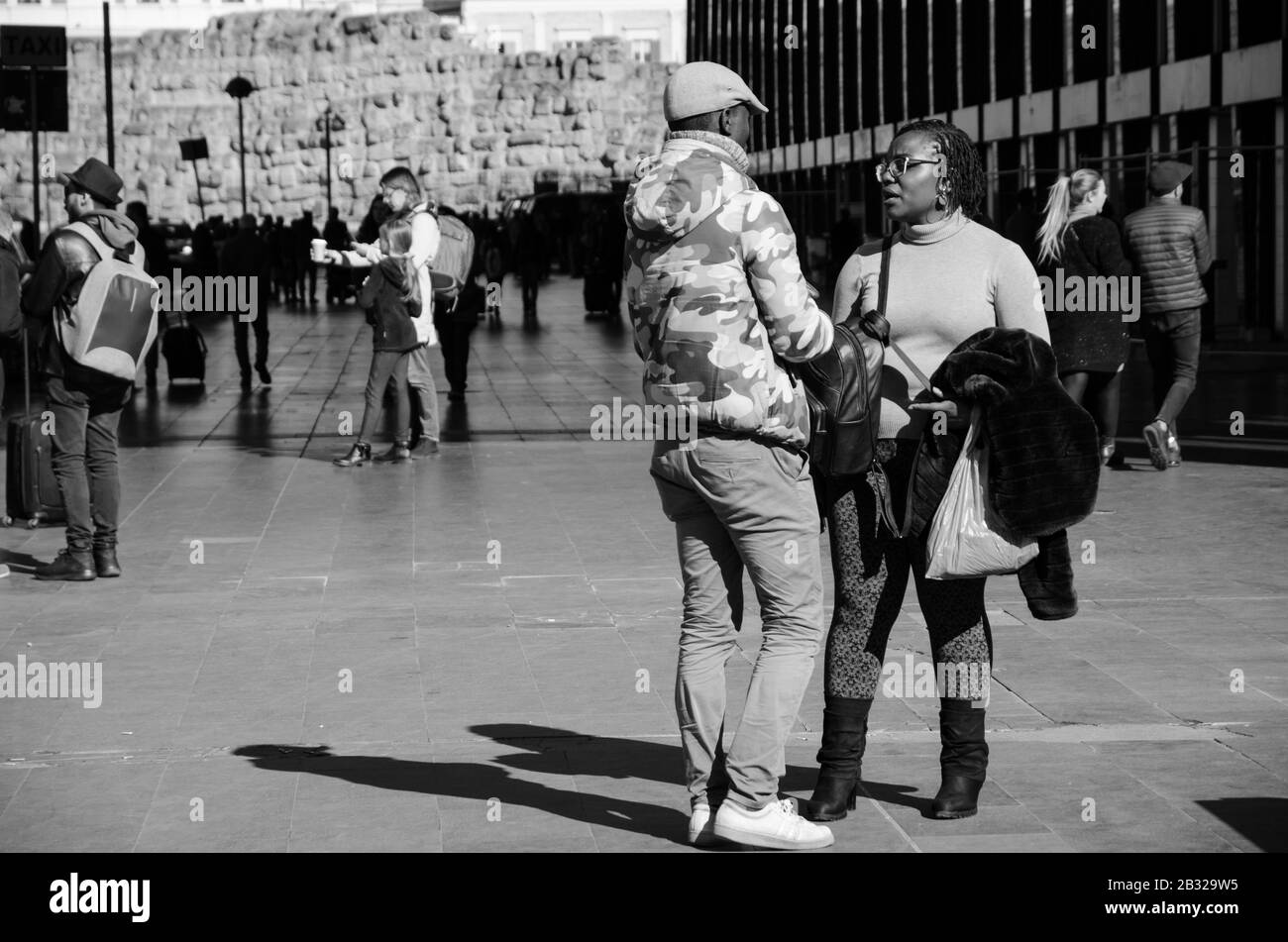 Rom, Italien. Februar 2020. Ein schwarzer Mann und eine schwarze Frau, die vor dem Bahnhof spricht. Schwarz-Weiß-Bild Stockfoto
