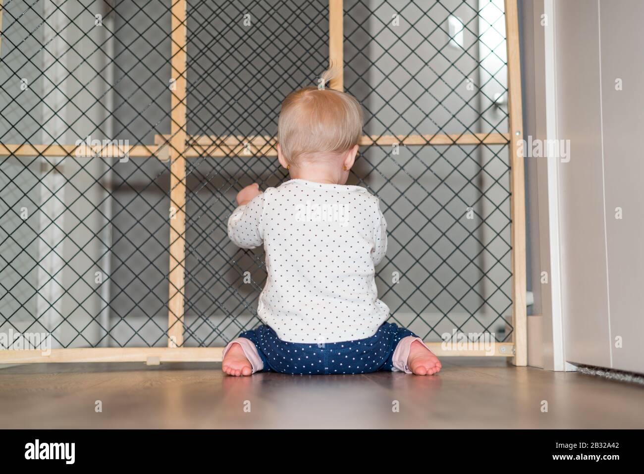 Süßes Baby Spielt Hinter Safety Gate Stockfoto