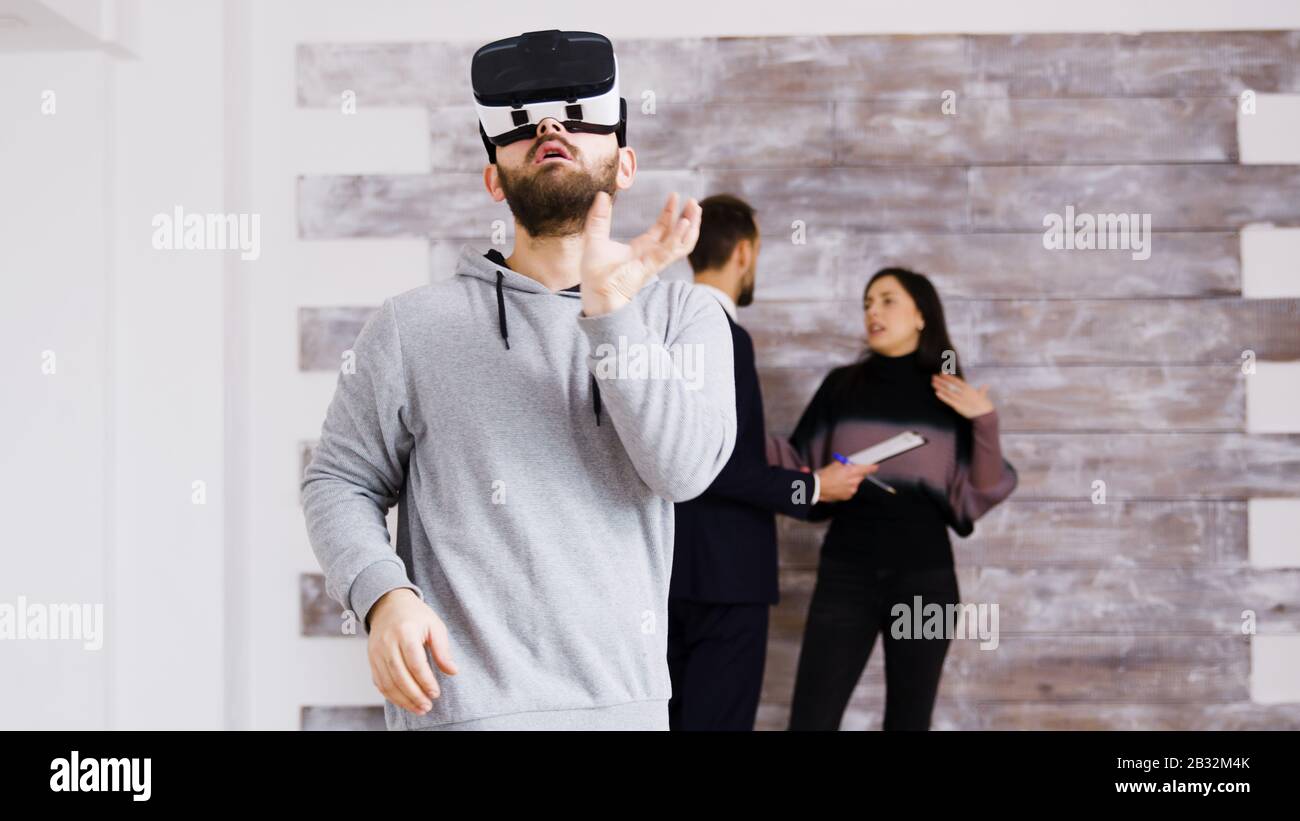 Erleben virtuelle Realität mit Headset in die neue Wohnung und Frau im Gespräch mit real estate agent im Hintergrund. Stockfoto
