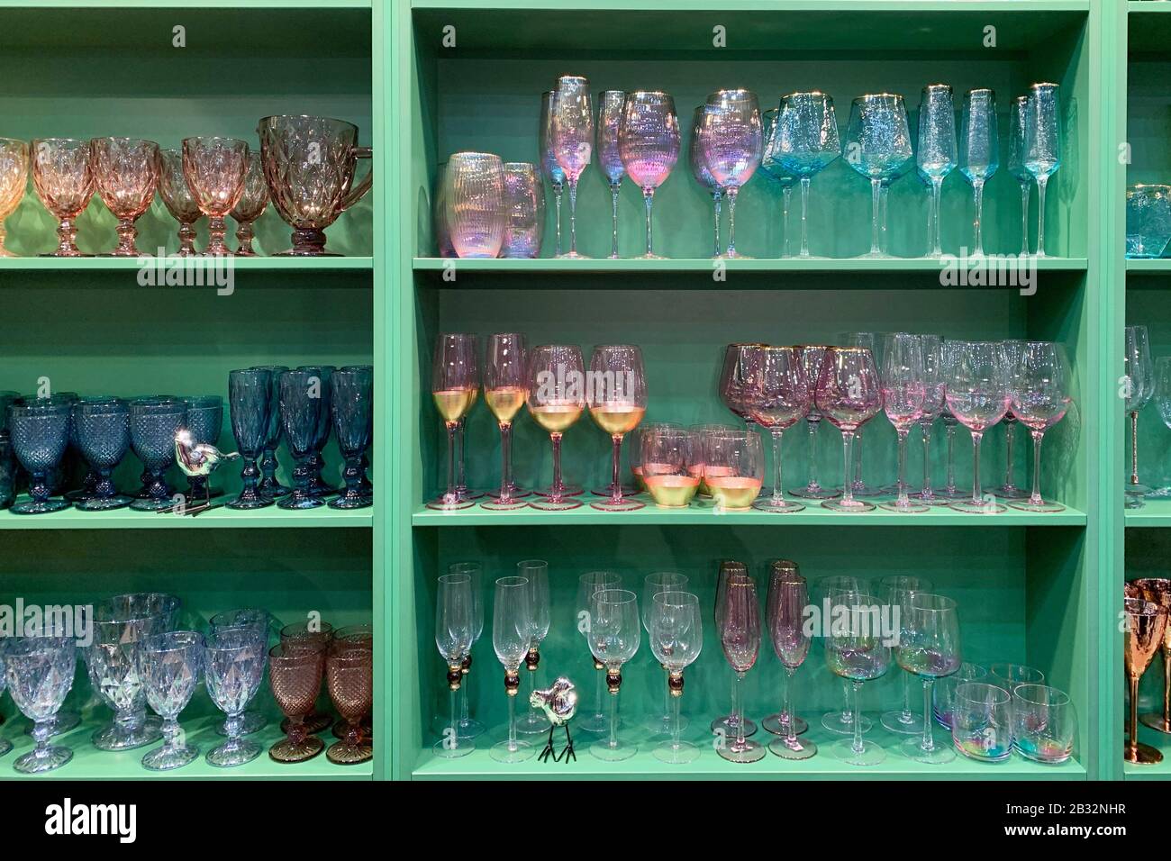 Sammlung von schönen bunten Gläsern auf Holzregalen Stockfoto