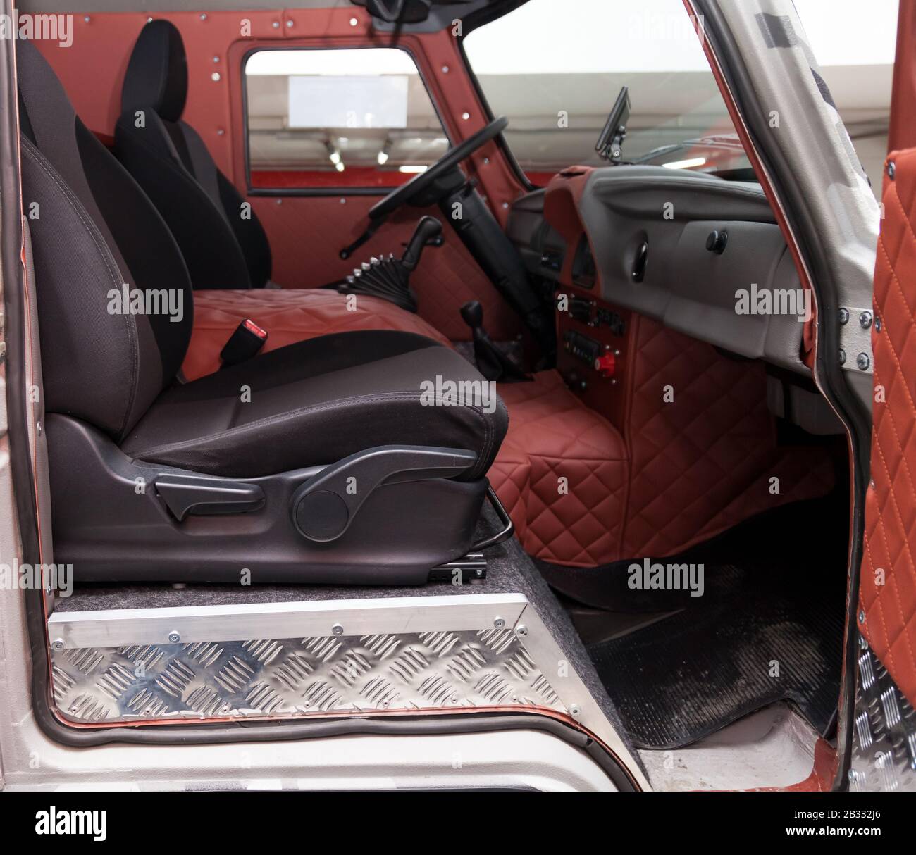 Bequeme Vordersitze im Fahrzeug: Fahrer und Beifahrer, mit rotem Leder,  Vintage-Interieur, das Lenkrad bedeckt einen Stockfotografie - Alamy