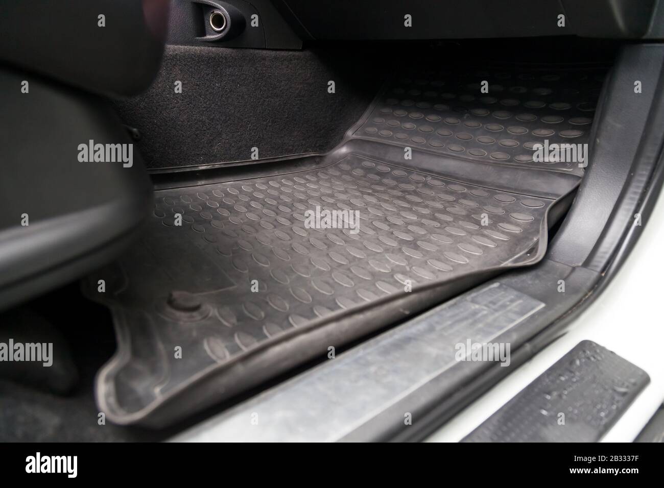 Schmutzige auto-fußmatten aus schwarzem gummi unter dem beifahrersitz in  der werkstatt für die fahrzeugaufbereitung vor der chemischen reinigung.  auto-service-industrie. innenraum einer limousine