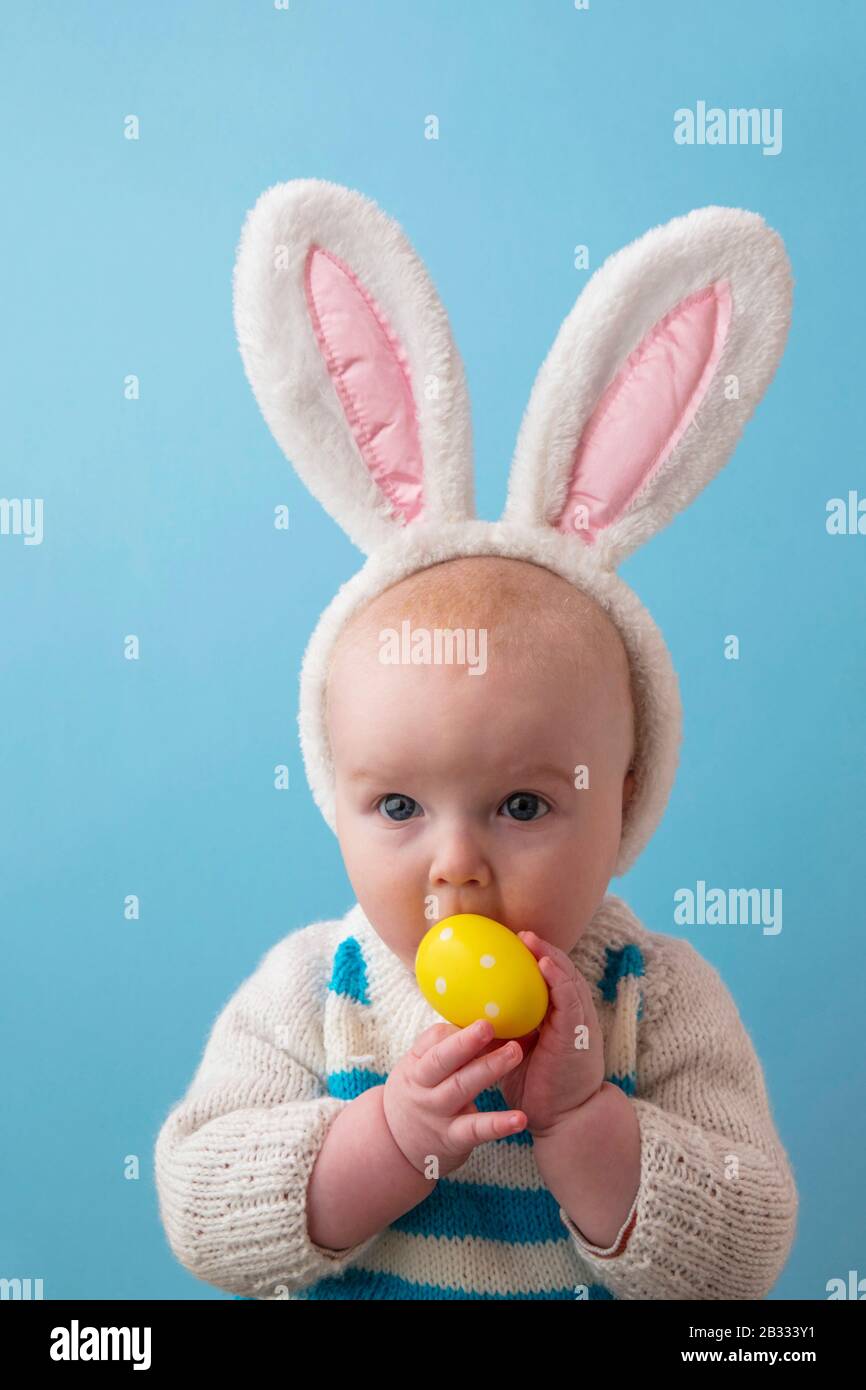 Süßes Baby mit osterbüschen, die mit einem osterei spielen Stockfoto