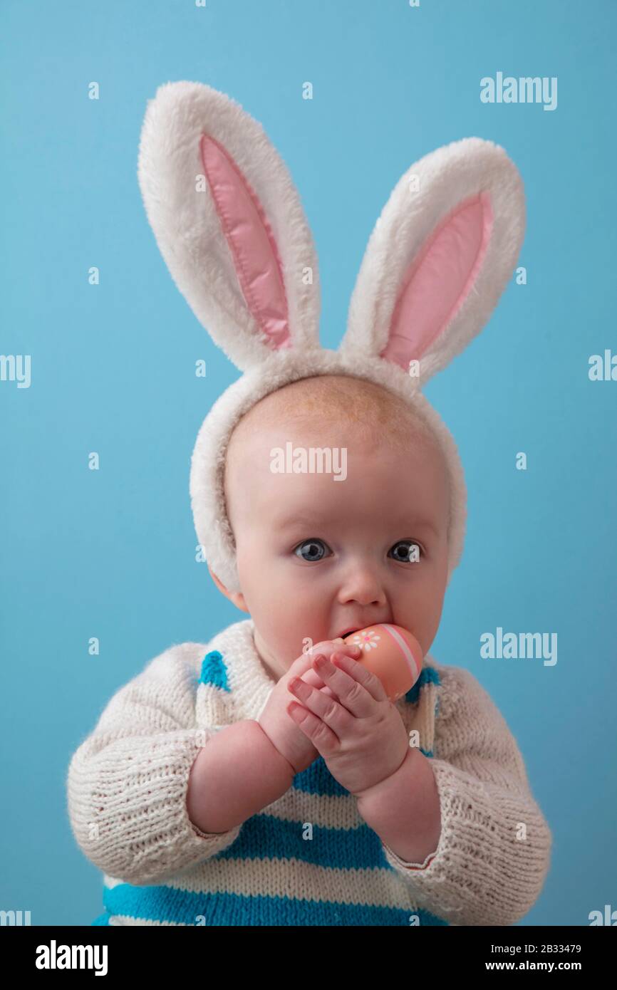 Süßes Baby mit osterbüschen, die mit einem osterei spielen Stockfoto