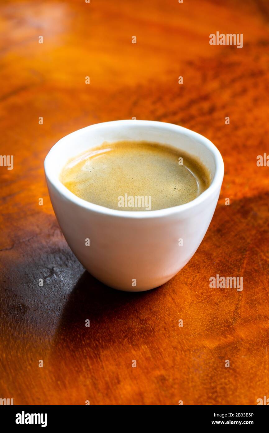 Tasse Kaffee in einem hübschen Hipper-Café. Weich fokussiertes Bild. Tasse Espresso auf dem alten Holztisch der Cafeteria. Stockfoto