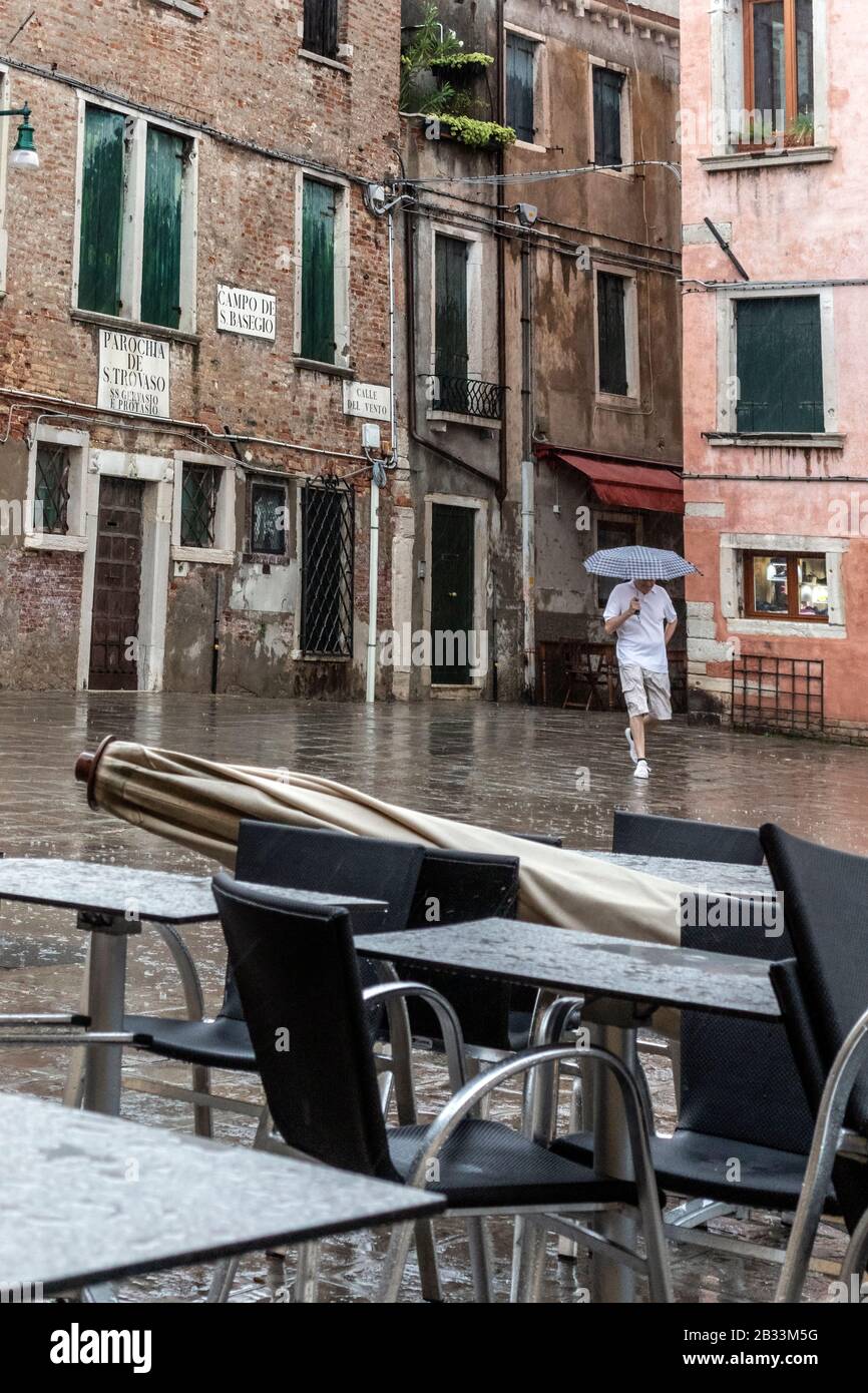 Ein einziger Mann, der mit Regenschirm durch den Regen geht, Venedig, Italien Stockfoto