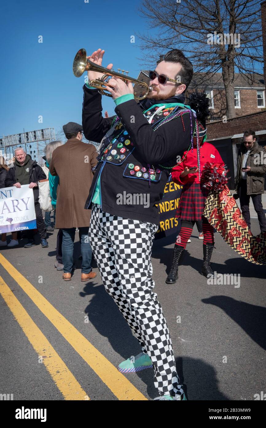 Ein Hungriger March-Band-Trompeter in Schachbretthosen erwärmt sich vor Beginn des St Patrick's Day für Alle Parade in Sunnyside, Queens, NYC. Stockfoto