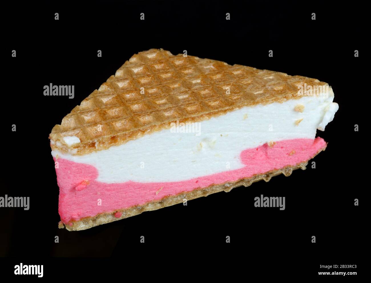 Kuchen aus dreieckigen Waffeln und cremigem, rosafarbenem Eis. Isoliert auf schwarzem Nacht-Food-Makro Stockfoto