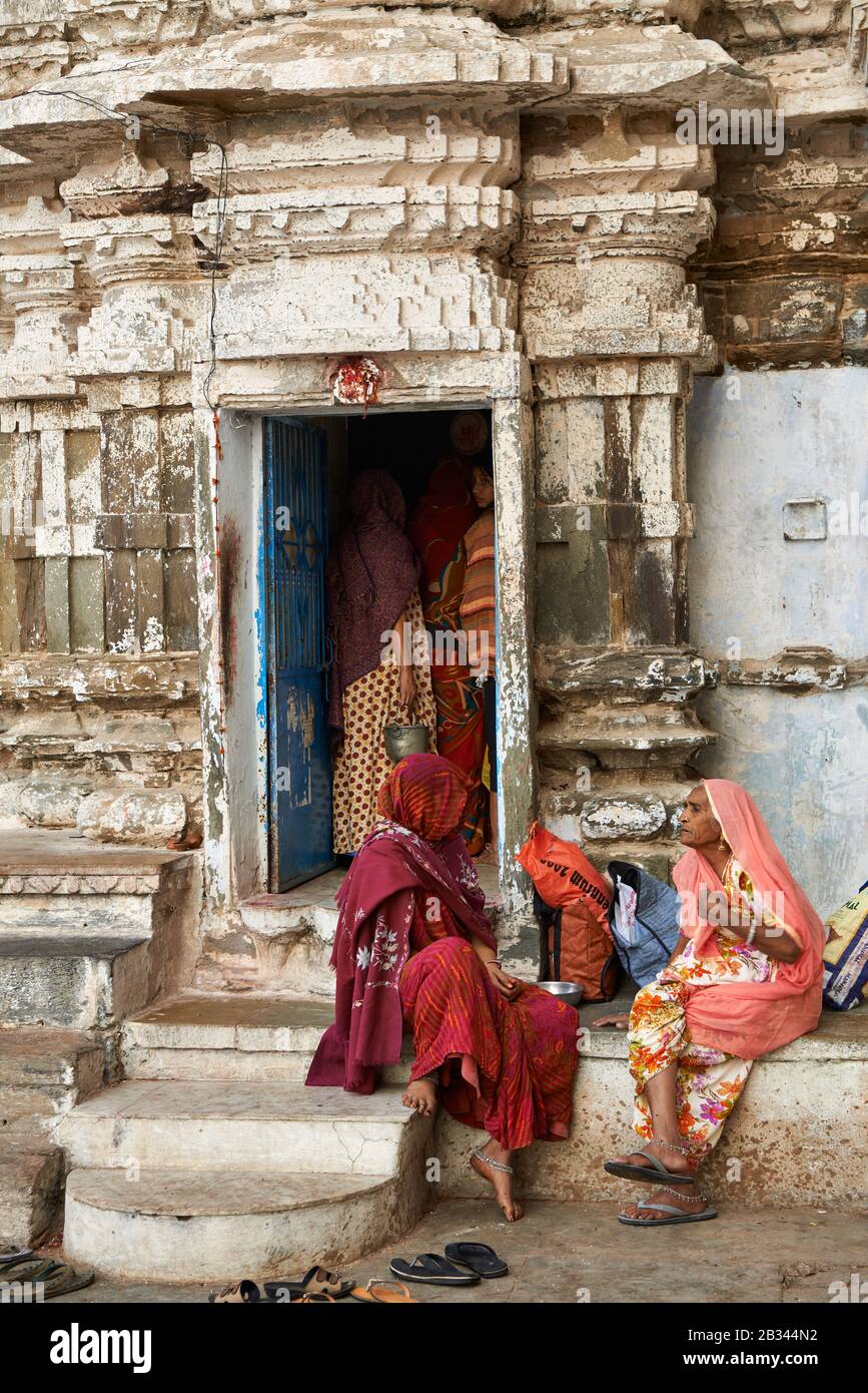 Frauen, die in farbenfrohen Saris an einem kleinen Hindutempel im Gangaur Ghat, Udaipur, Rajasthan, Indien gekleidet sind Stockfoto