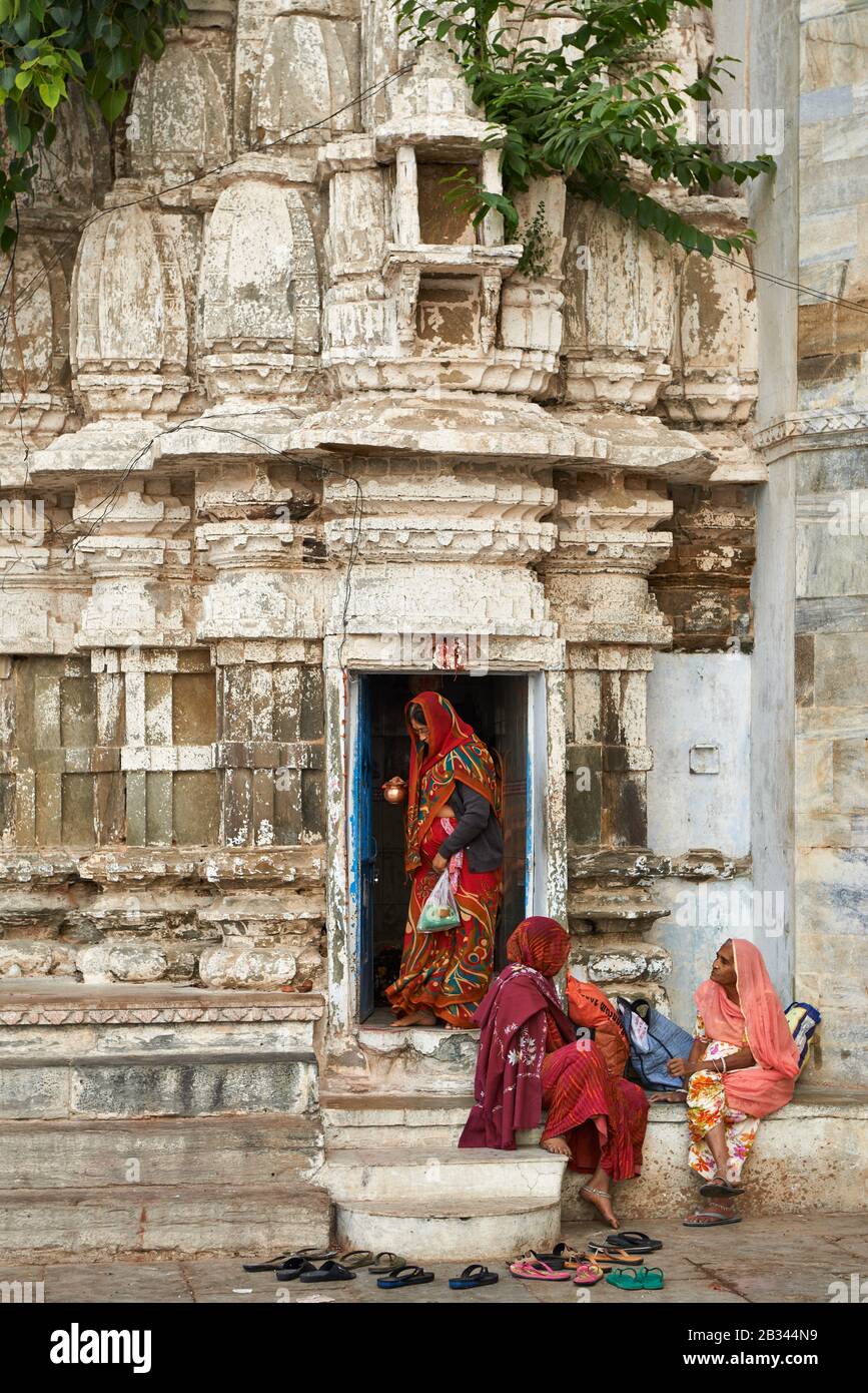 Frauen, die in farbenfrohen Saris an einem kleinen Hindutempel im Gangaur Ghat, Udaipur, Rajasthan, Indien gekleidet sind Stockfoto