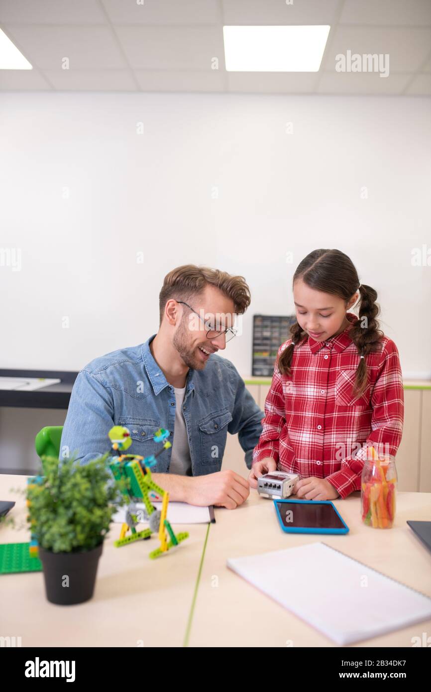 Mädchen, die die Steuereinheit betrachten und etwas mit der Lehrerin besprechen Stockfoto