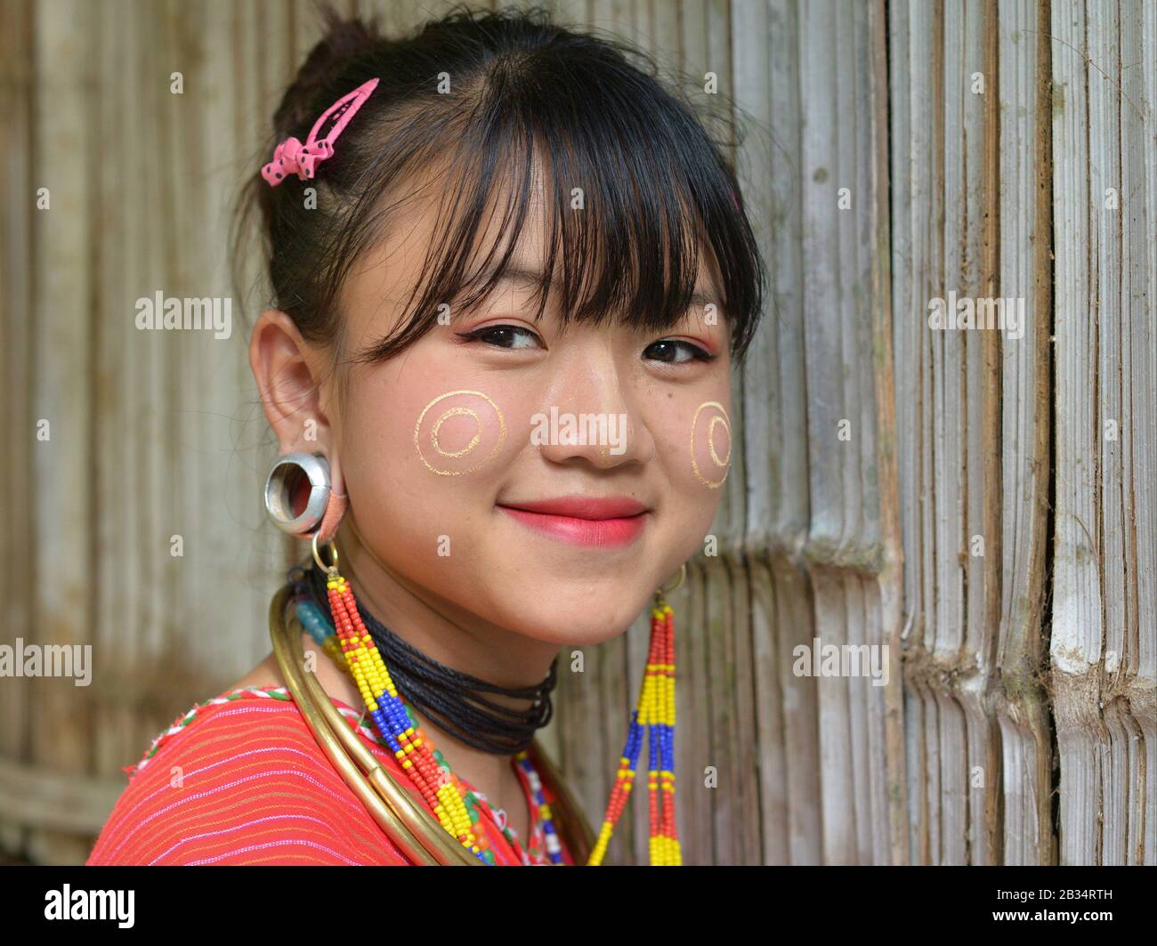 Hübsches Kayaw (Kayor) Teenager-Mädchen mit traditionellen burmesischen Thanaka Gesicht Kosmetik auf ihren Wangen und markante Tribal-Ohrenstöpsel für die Kamera. Stockfoto