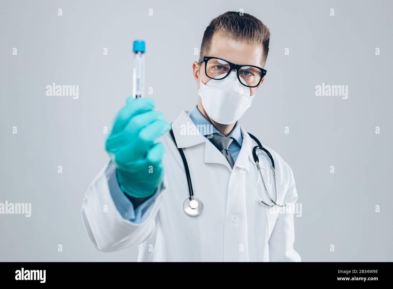 Arzt, der Atemschutzmaske trägt und die Blutprobe Coronavirus Covid-19 hält Stockfoto