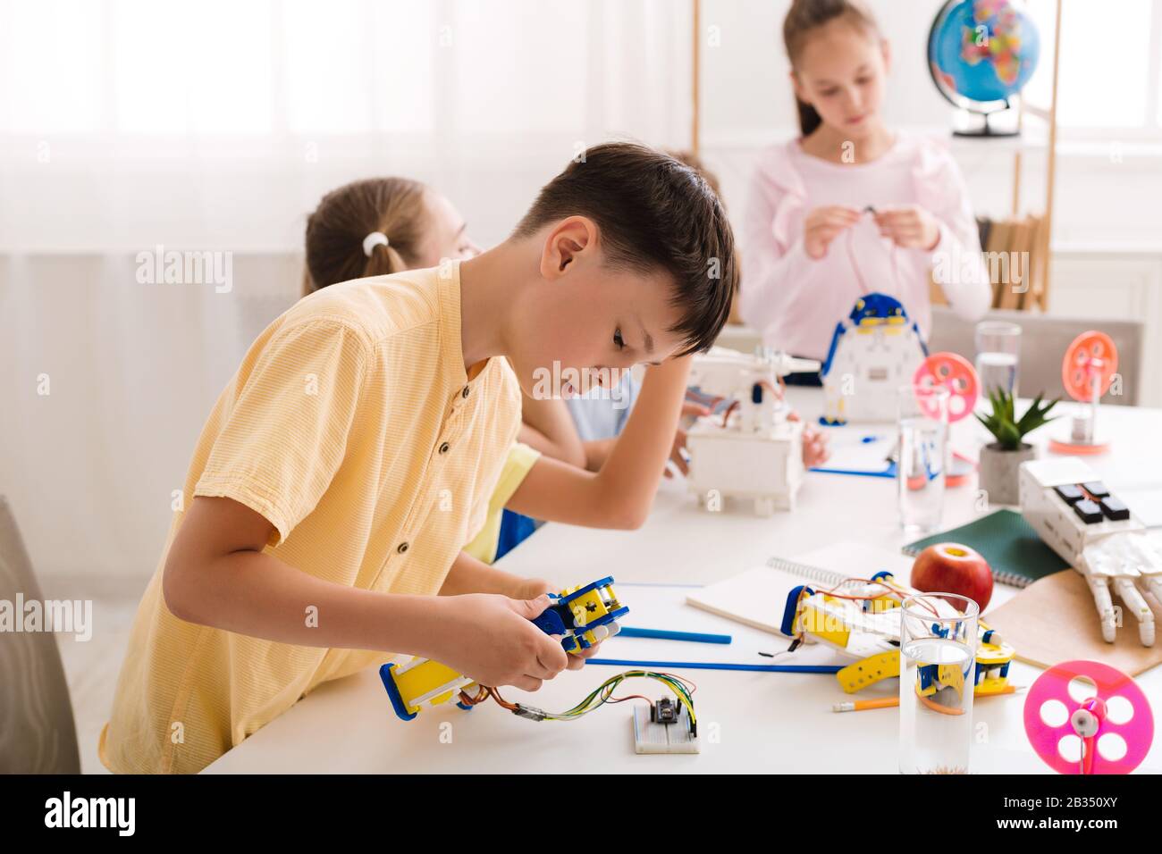 Konzentrierter Teenager, der Roboter in der Klasse konstruiert Stockfoto