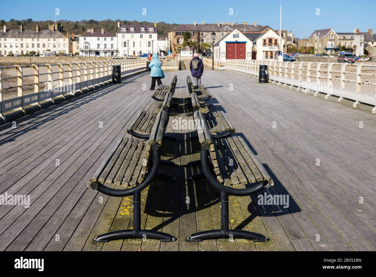 Blick zurück entlang des Piers mit leeren Bänken in der Küstenstadt Beaumaris, Insel Anglesey, Nordwales, Großbritannien Stockfoto