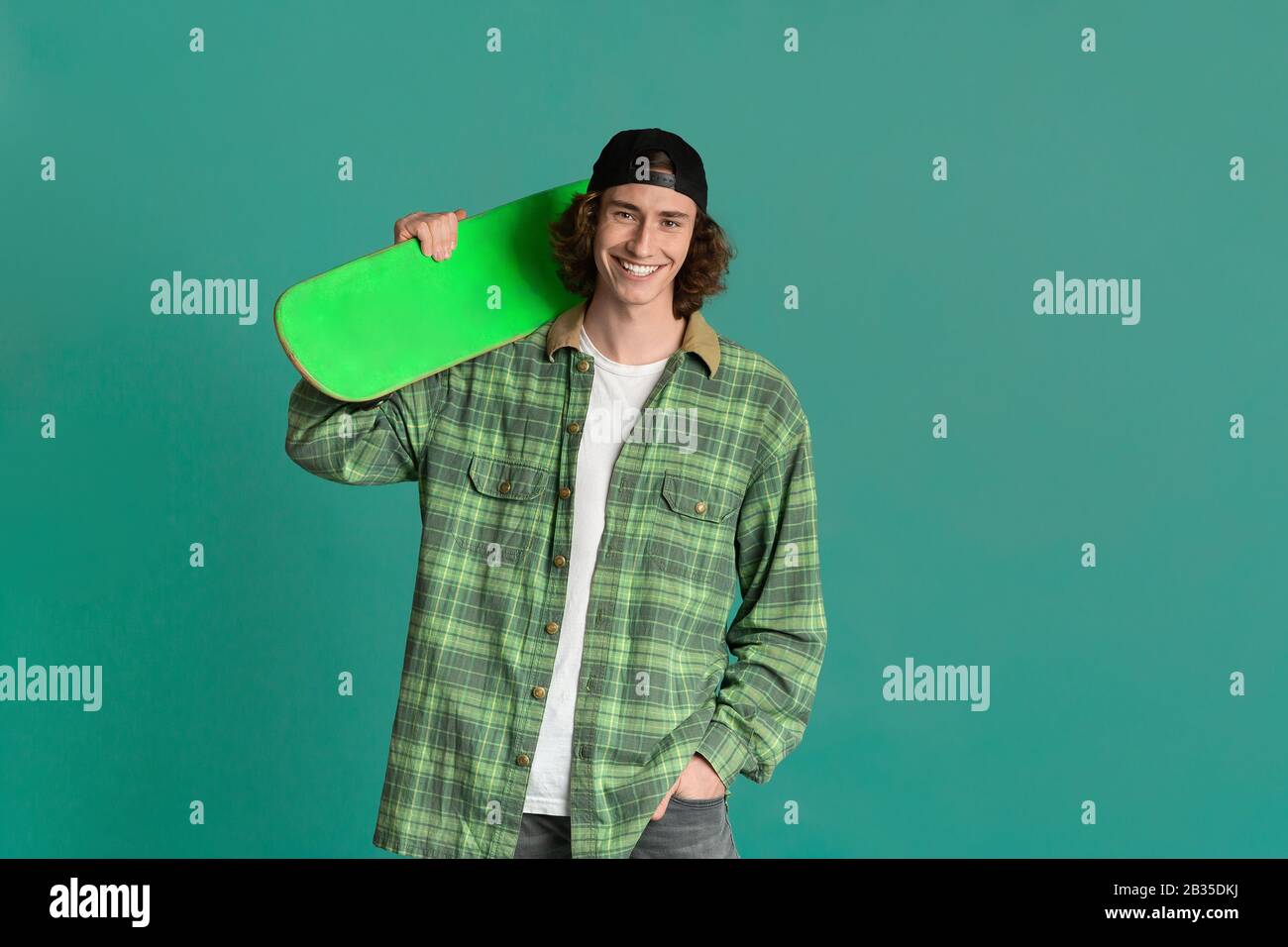 Teenager-Kultur-Konzept. Funky junger Mann mit Skatebord auf Farbhintergrund, Platz für Text Stockfoto