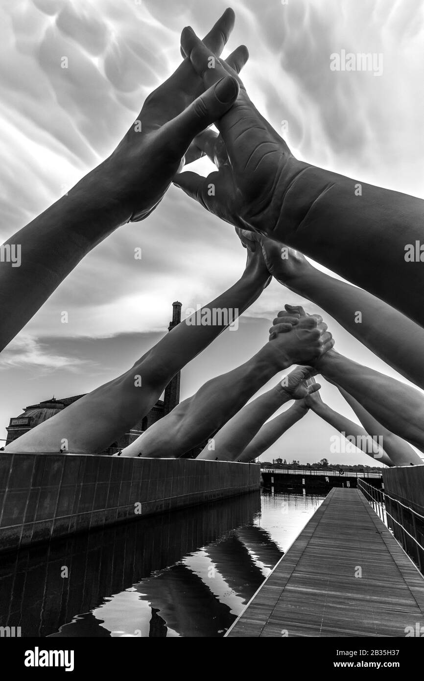 Der italienische Künstler Lorenzo Quinn baut Brücken über Venice Arsenale, Italien. Sechs Paar Hände, die eine Brücke über eine Venedig-Wasserstraße schaffen, symbolisieren die Notwendigkeit, Brücken zu bauen und Trennungen zu überwinden. Stockfoto