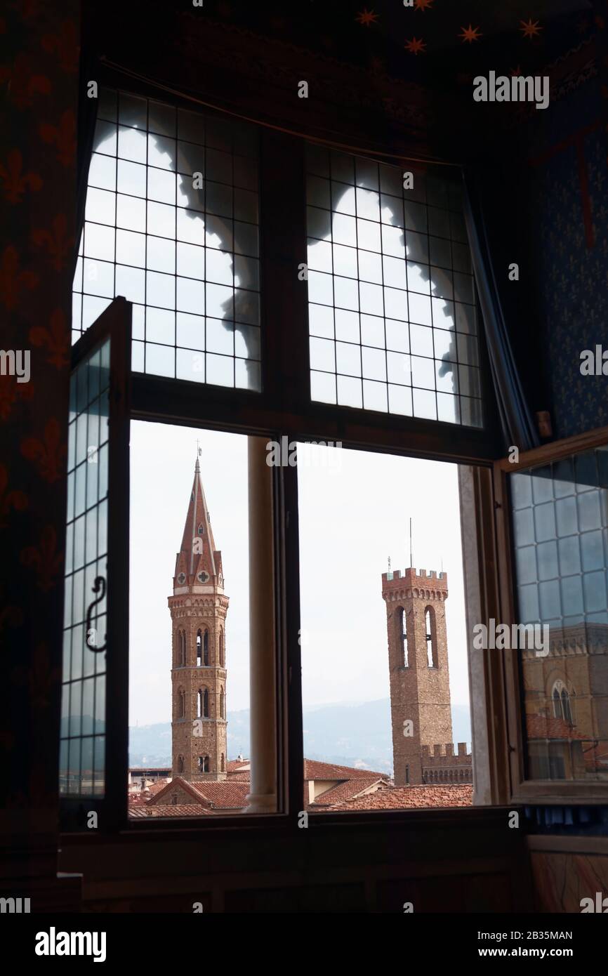 Der Glockenturm der Kirche Badìa Fiorentina (links) und der Turm des Palazzo del Bargello in Florenz, Italien, aus dem mittelalterlichen Fenster betrachtet Stockfoto