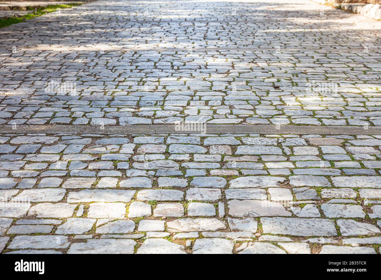 Gepflasterter Fußweg aus altem Steinmarmor, Hintergrund des Kopfsteinpflasterweges, Textur. Perspektivische Ansicht mit hohem Winkel Stockfoto