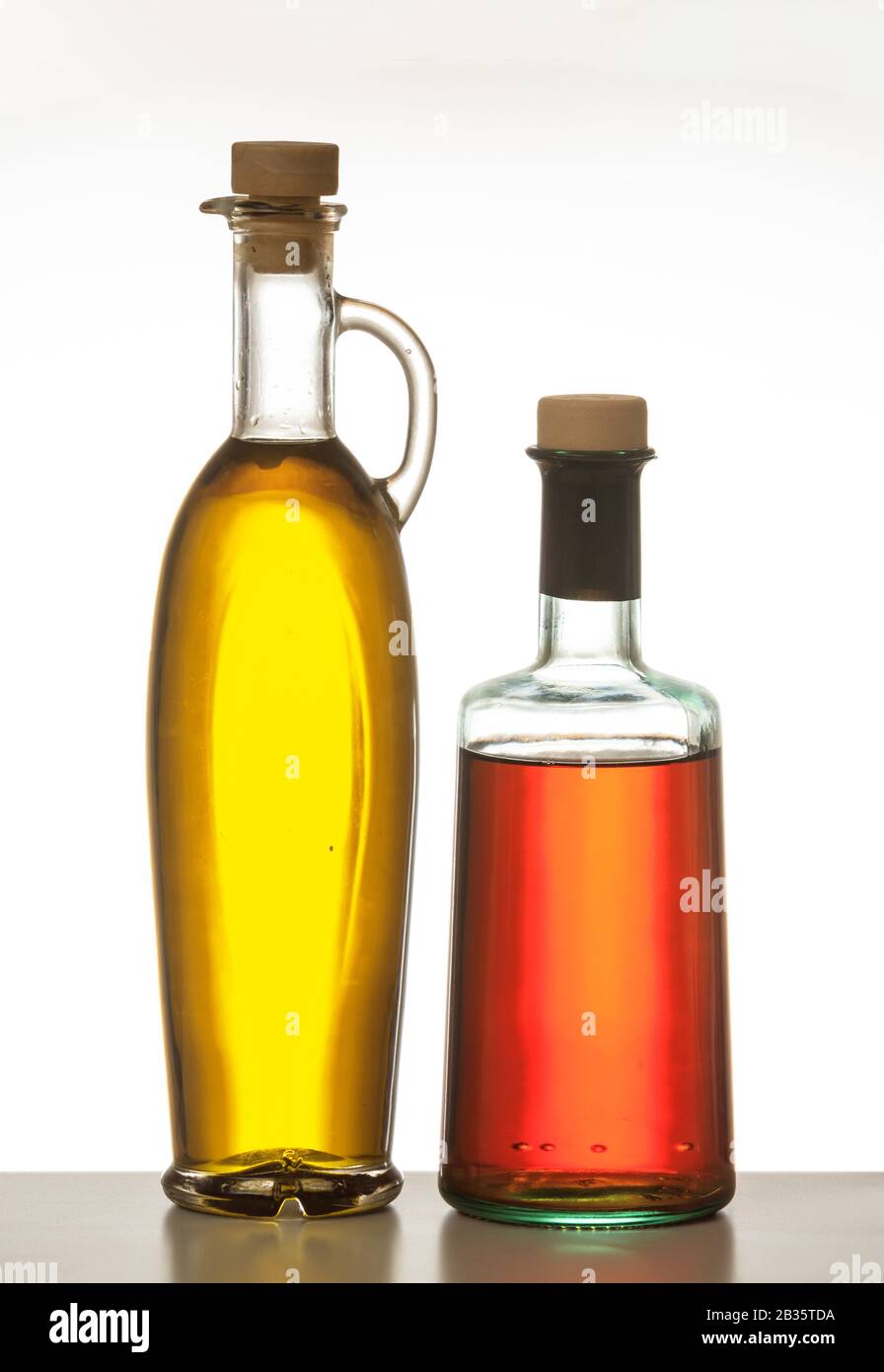Olivenöl- und Essigflaschen isoliert. Transparente Glasflaschen mit Korkstopfen isoliert vor weißem Hintergrund. Natives Olivenöl extra und rot Stockfoto