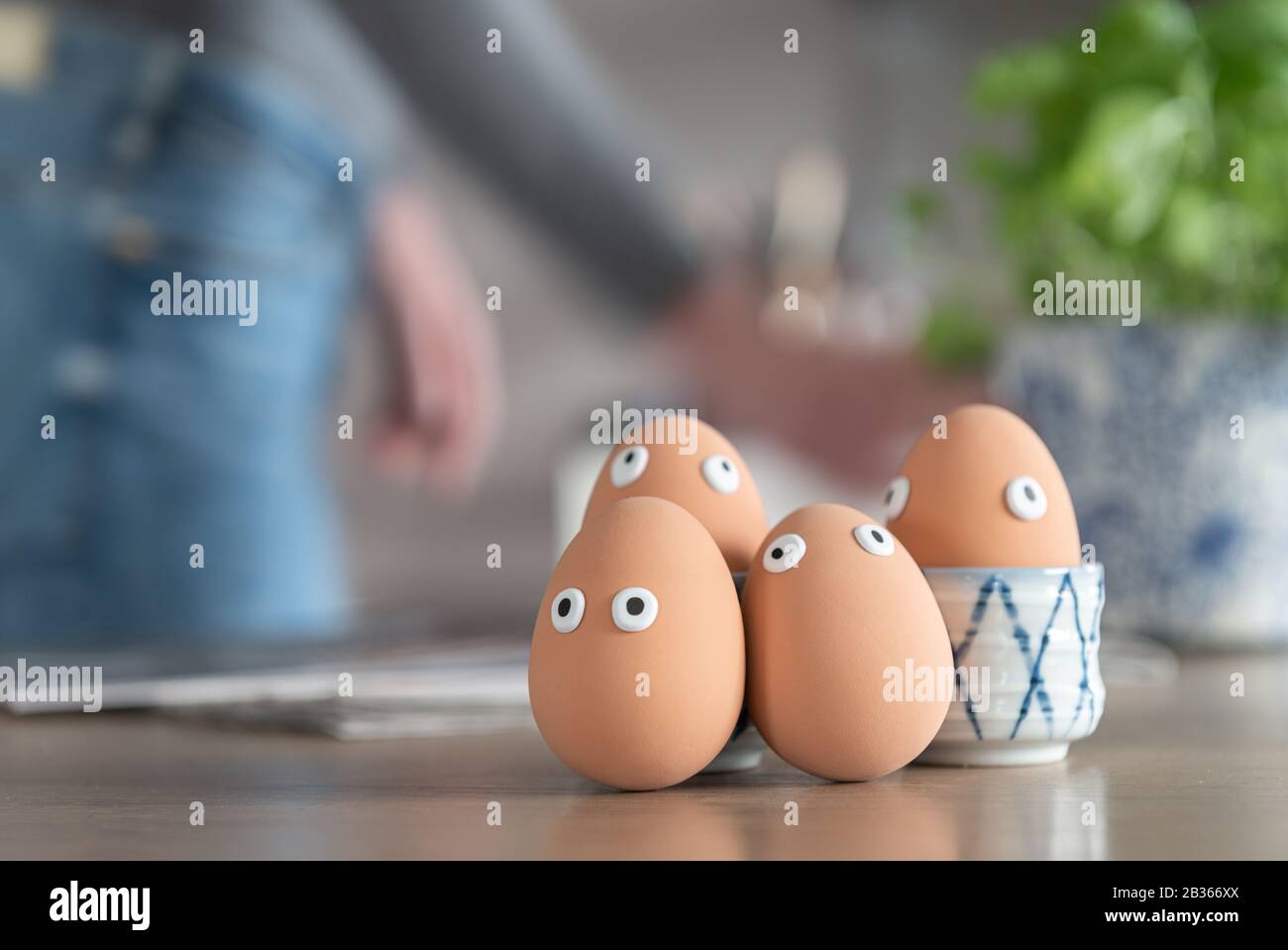 Fröhliche ostereier auf dem Küchentisch, ostereierjagd, Eierfiguren mit lustigen Gesichtern, osterkonzept, Küche im Hintergrund, osterthema, Stockfoto