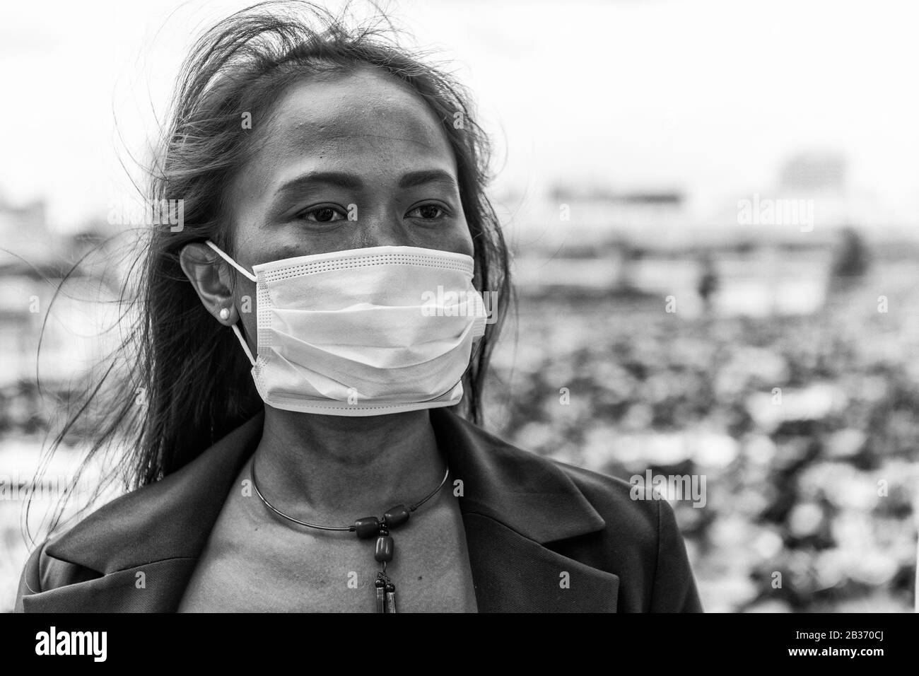 Asiatische Frau, die im Freien Zeit mit hygienischer Maske genießt, um das Virus PM2,5 und Coronavirus zu verhindern. Luftverschmutzung, Konzept des Umweltbewusstseins. Stockfoto